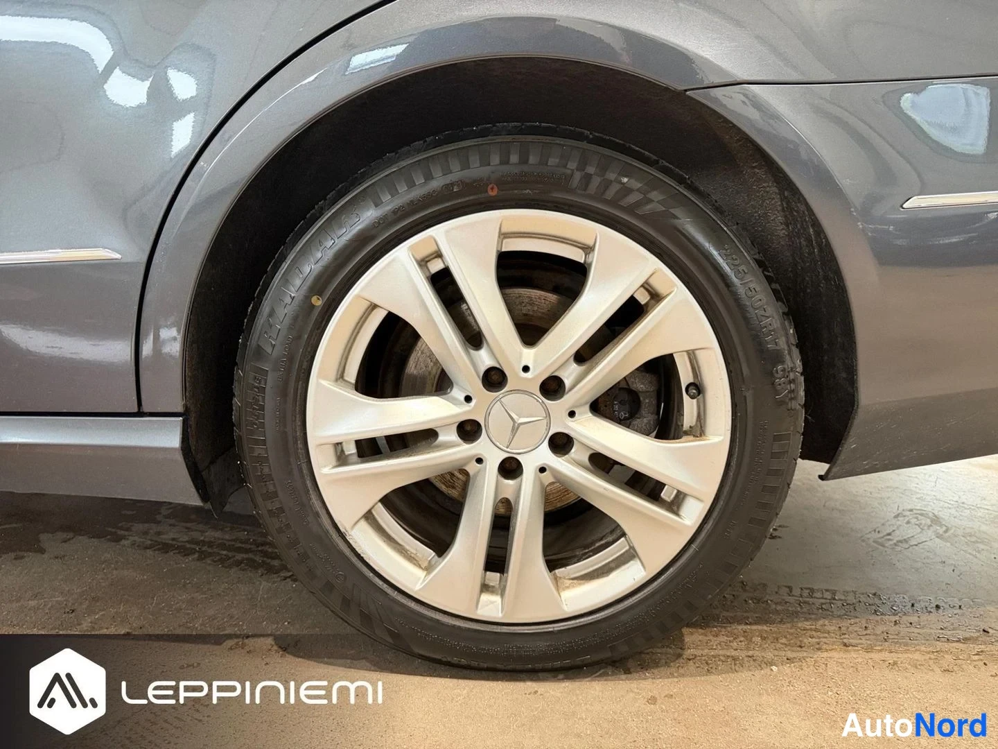 Muu: Tummanharmaan auton etupyörä hopeisella Mercedes-tähtivanteella lähikuvassa sisätilassa