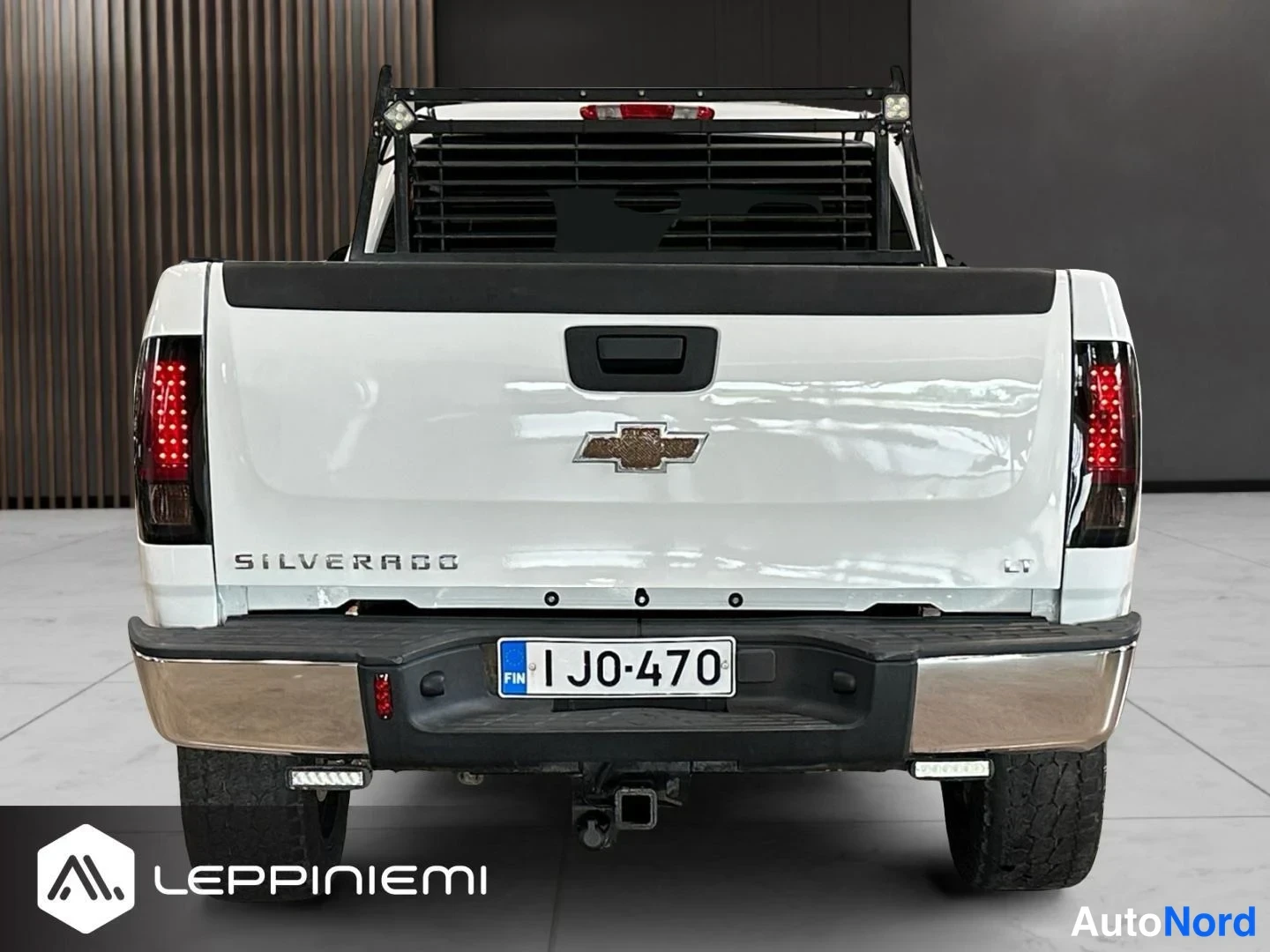 Takaa: Valkoisen lava-auton takanäkö: SILVERADO-teksti, Chevrolet-logo, LT-merkki, rekisterikilpi ja perävaunukytkin.