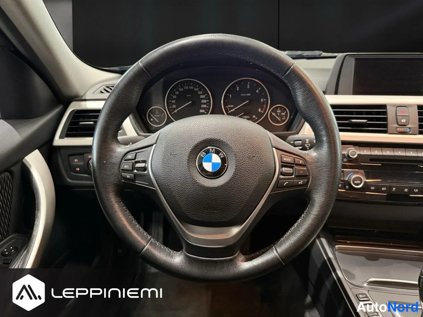Edestä: Ohjauspyörän lähikuva: BMW-monitoimiOhjauspyörä ja analogiset mittarit.