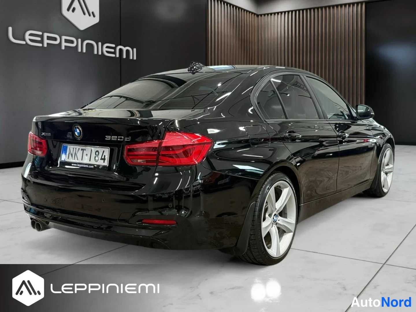 Takaviisto: Mustan BMW-sedanin takakulma vasemmalta kuvattuna; näkyvät takavalot, moottoritilan kansi ja rekisterikilpi.