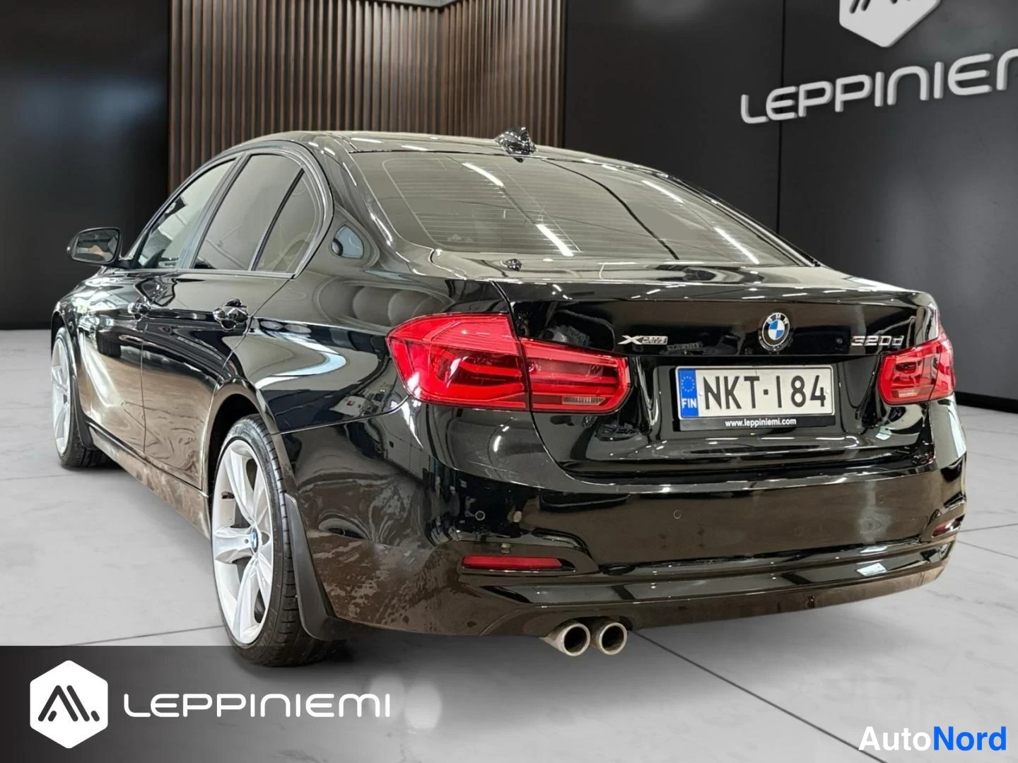 Takaviisto: Musta BMW 320d kolmannelta takakulmalta, rekisterikilpi, hopeavatkat ja kaksoispakoputket näkyvissä.