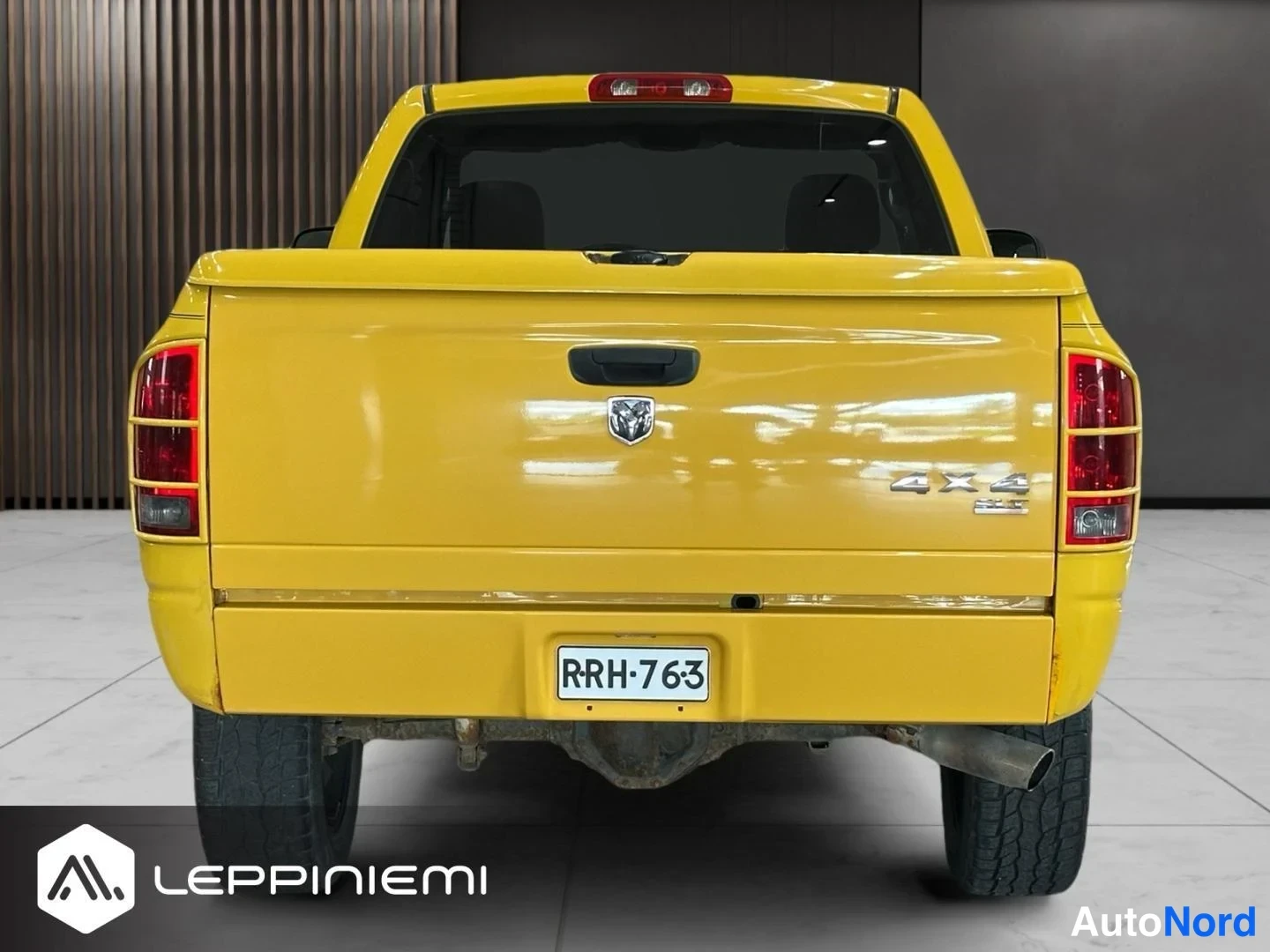Takaa: Keltainen nakkaila-merkkinen avolavakoen suoraan takaa; rekisterikilpi, 4x4-teksti, DODGE-embleemi ja pakoputki näkyvät.