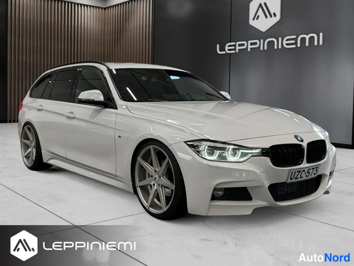 Etuviisto, nokka oikealle: Valkoisen BMW-farmarin etukulmanäkymä oikealta; musta etusäleikkö, rekisteri ja hopeat kevytmetallivanteet.