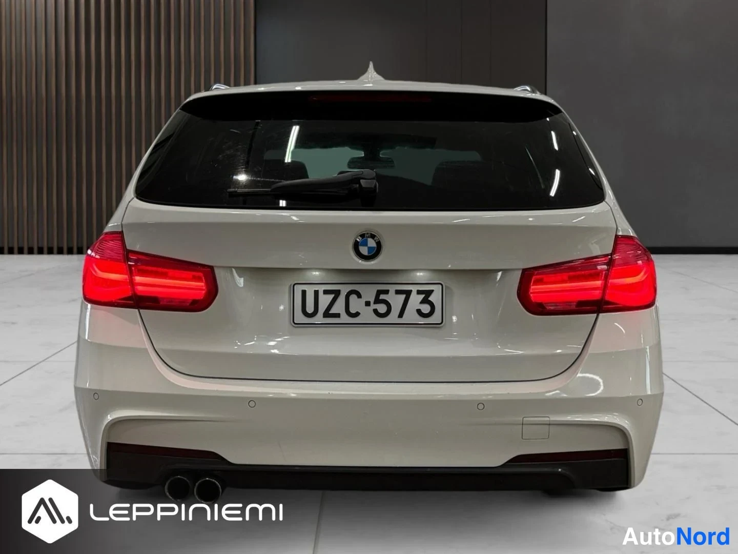 Takaa: BMW Touring -farmarin takaa suoraan kuvattuna: punaiset takavalot, -rekisterikilpi, kattospoileri ja kaksoisputkinen pakopuhti. Kori vaalea.