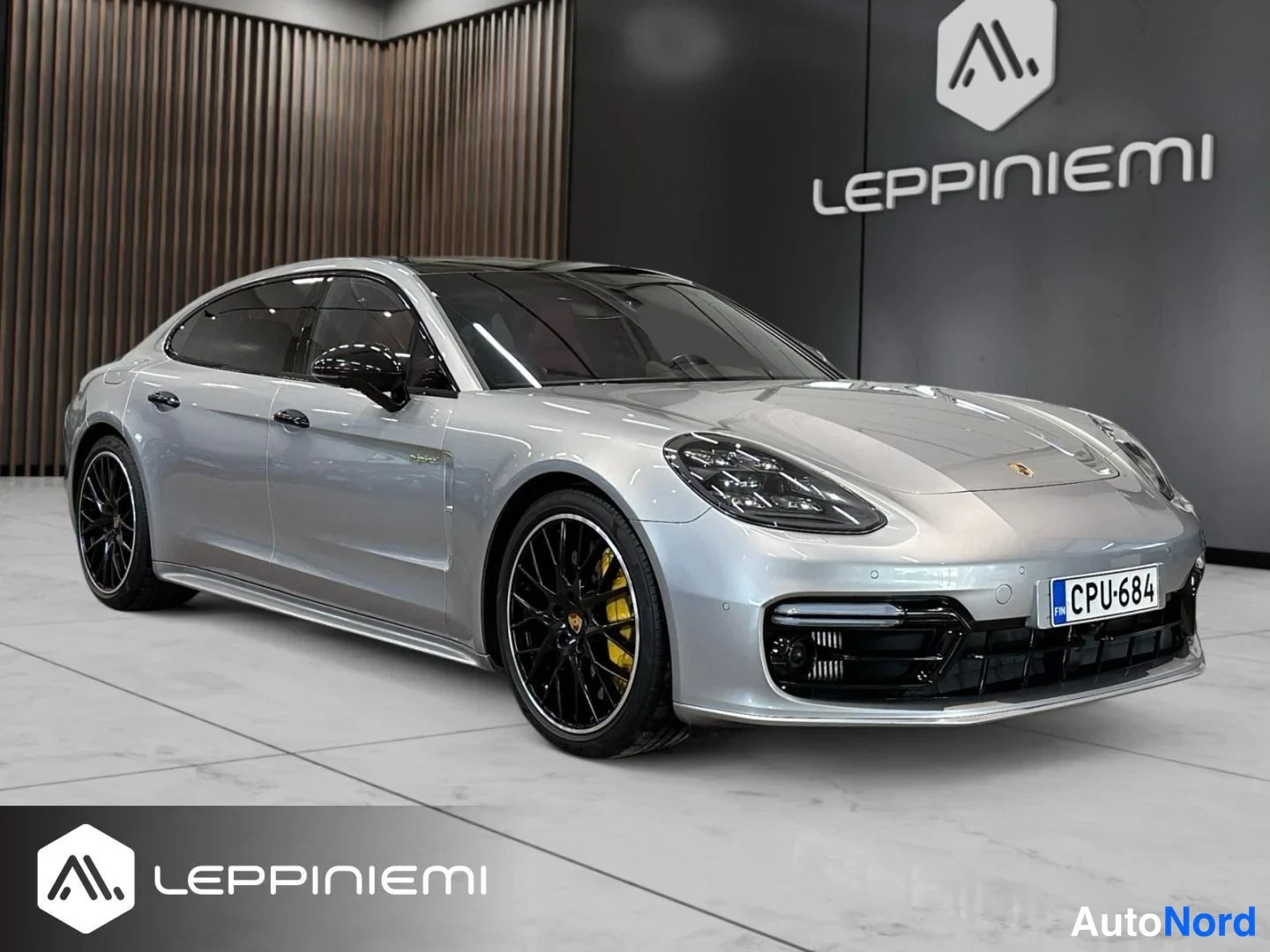 Etuviisto, nokka oikealle: Hopeanharmaa Porsche Panamera Kolme neljännestä edestä oikeaan etukulmaan, mustat vanteet ja keltainen jarrusatula näkyvissä, rekisterikilpi.