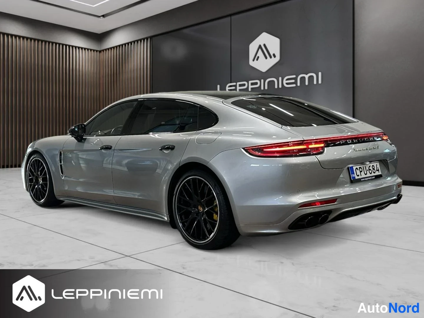 Takaviisto: Porsche Panamera -auton takakulma toiselta puolelta: hopeakarmea yhtye, mustat kevytmetallivanteet, rekisterikilpi.
