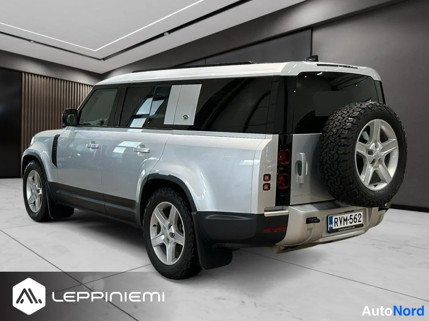 Takaviisto: Land Rover Defenderin takaosan kolmasosa vasemmalta: pitkä akseliväli, varaossa pyörä ja rekisterikilpi, hopeanvärinen kori.