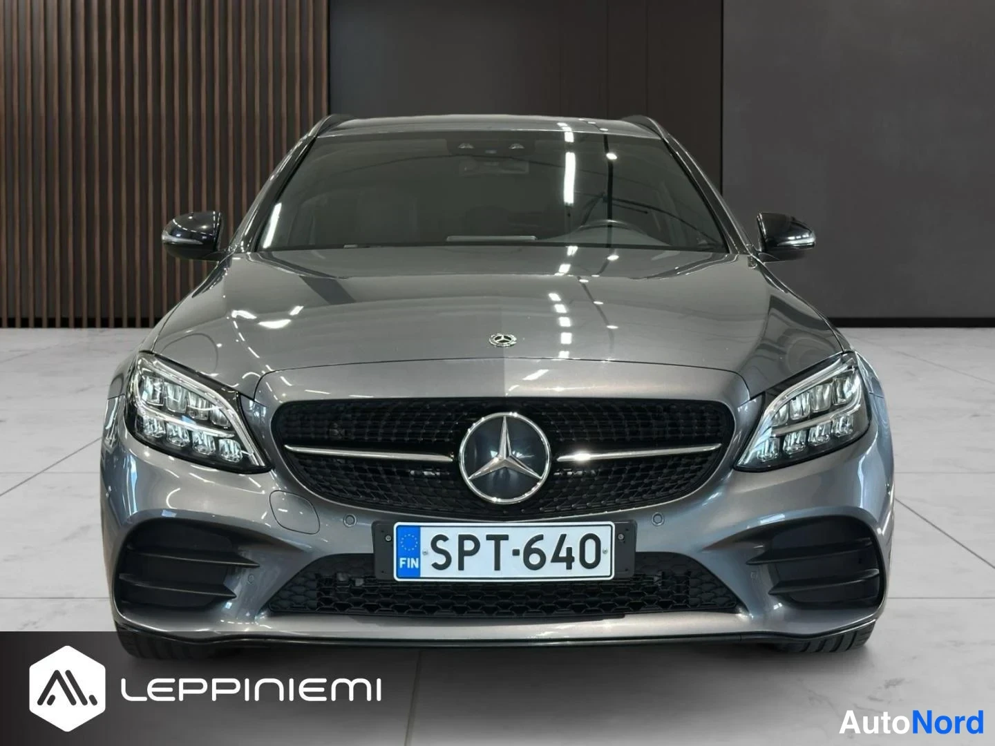 Edestä: Mercedes-Benz C-sarjan farmariauto suoraan edestäpäin kuvattuna, harmaaksi maalattu runko.