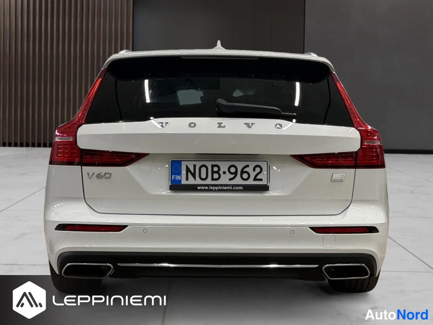 Takaa: Valkoisen farmariauton suora takanäkymä, VOLVO-merkintä ja rekisterikilpi.