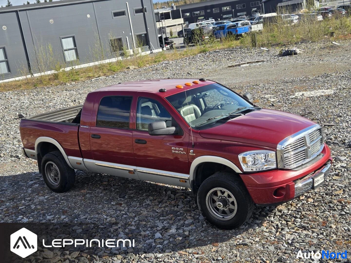Etuviisto, nokka vasemmalle: Tummametallichkilpunainen Dodge Ram 2500 lava-avolla kalliotarhalla, etukulma vasemmalta