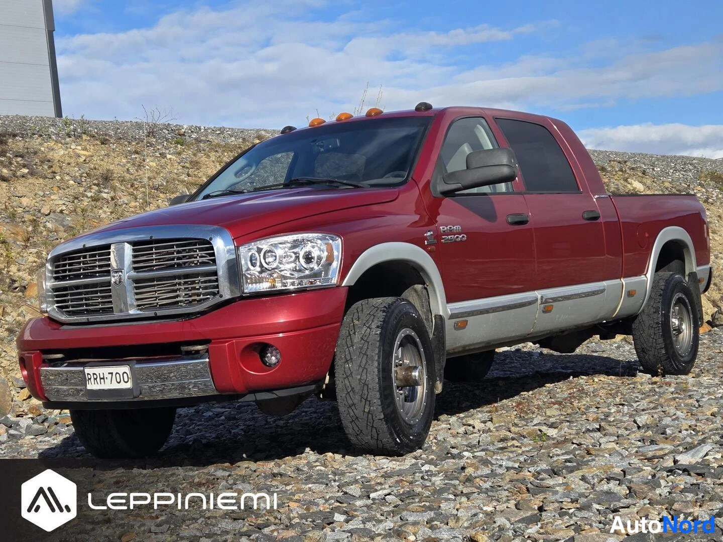 Etuviisto, nokka vasemmalle: Tummametallichkilpunainen Dodge Ram 2500 sora-alueella, etukulma vasemmalta