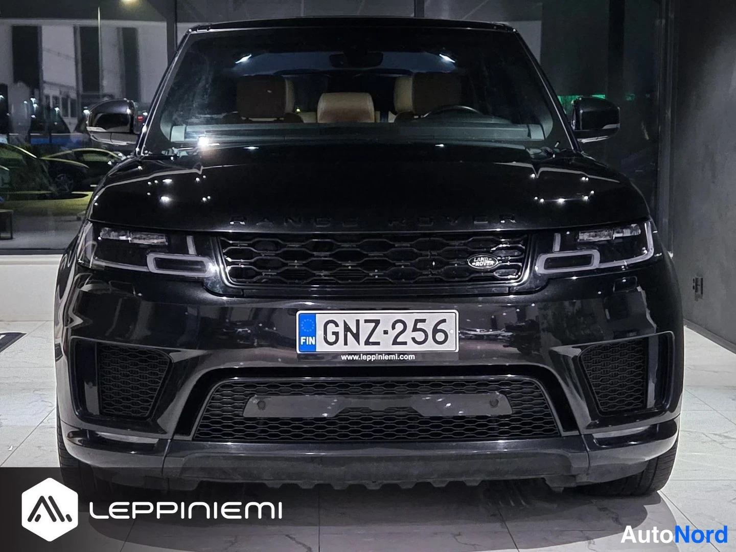 Edestä: Musta Land Rover Range Rover Sport suoraan edestä, etusäleikössä Land Rover -merkki, rekisteritunnus.