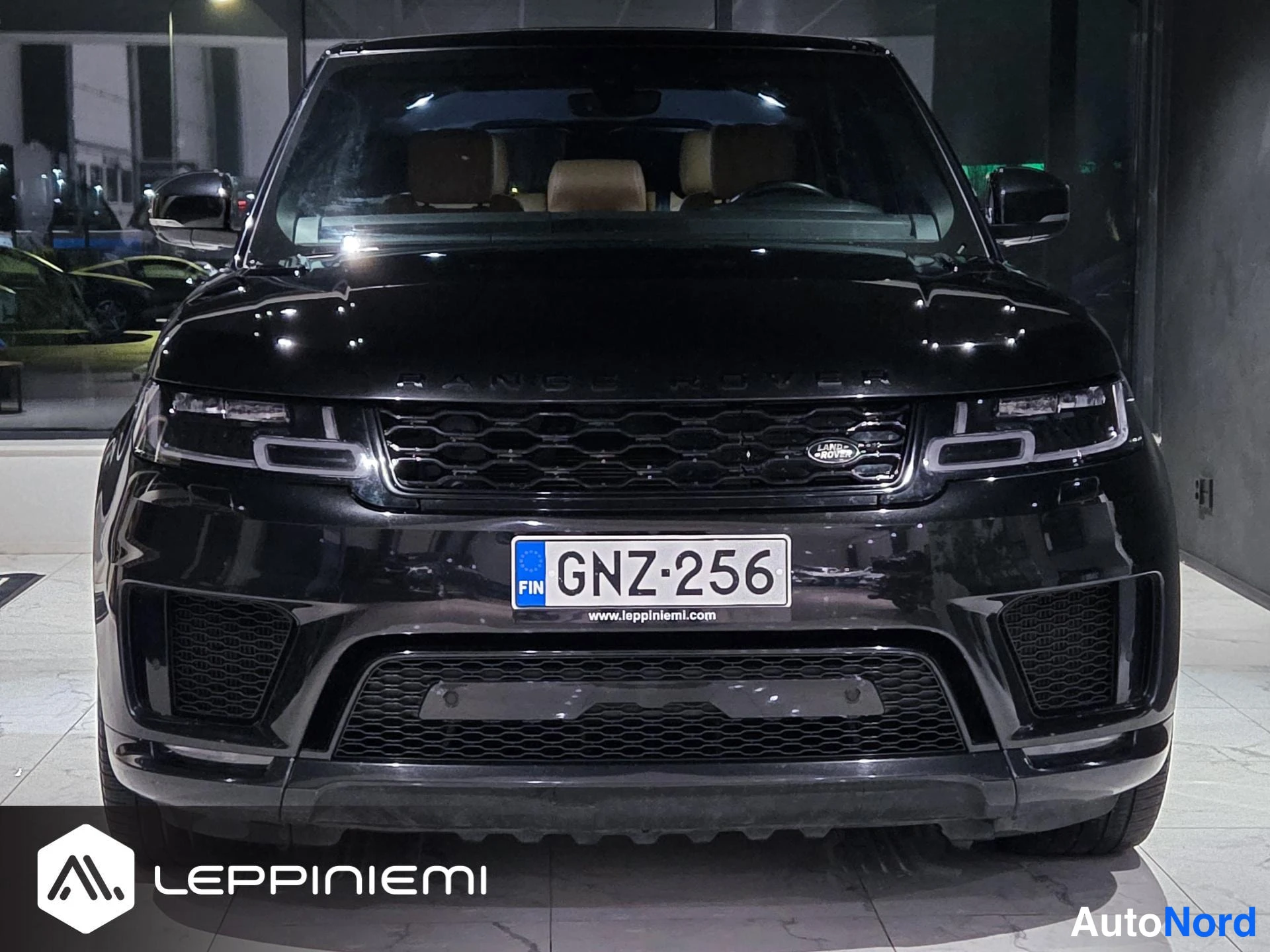Edestä: Mustan Land Rover Range Rover Sportin etunäkymä suoraan edestä, rekisteritunnus, Network-tyylinen etusäleikkö ja Land Rover -merkki näkyvät.