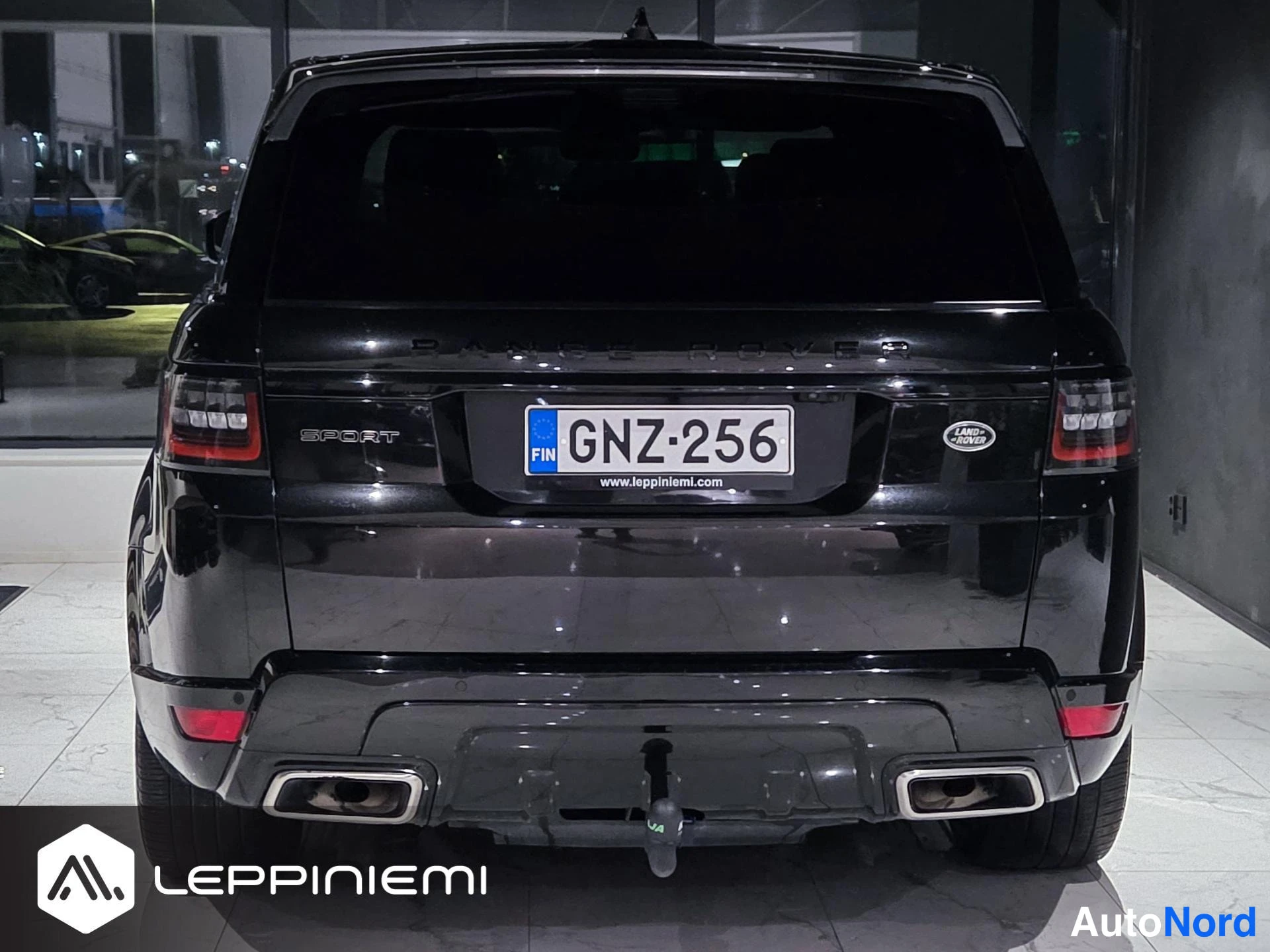Takaa: Mustan Land Rover Range Rover Sportin takanäkymä suoraan takaa, rekisteritunnus, SPORT-teksti, neliöpakoputket ja vetoauto-kytkin näkyvät.