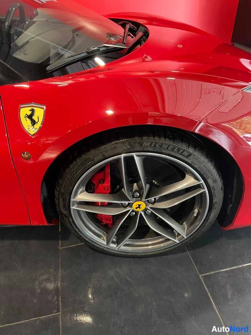 Sivulta: Punaisen auton etupyörän lähikuva, Michelin-merkitty rengas ja Ferrari-tunnus konepellissä.