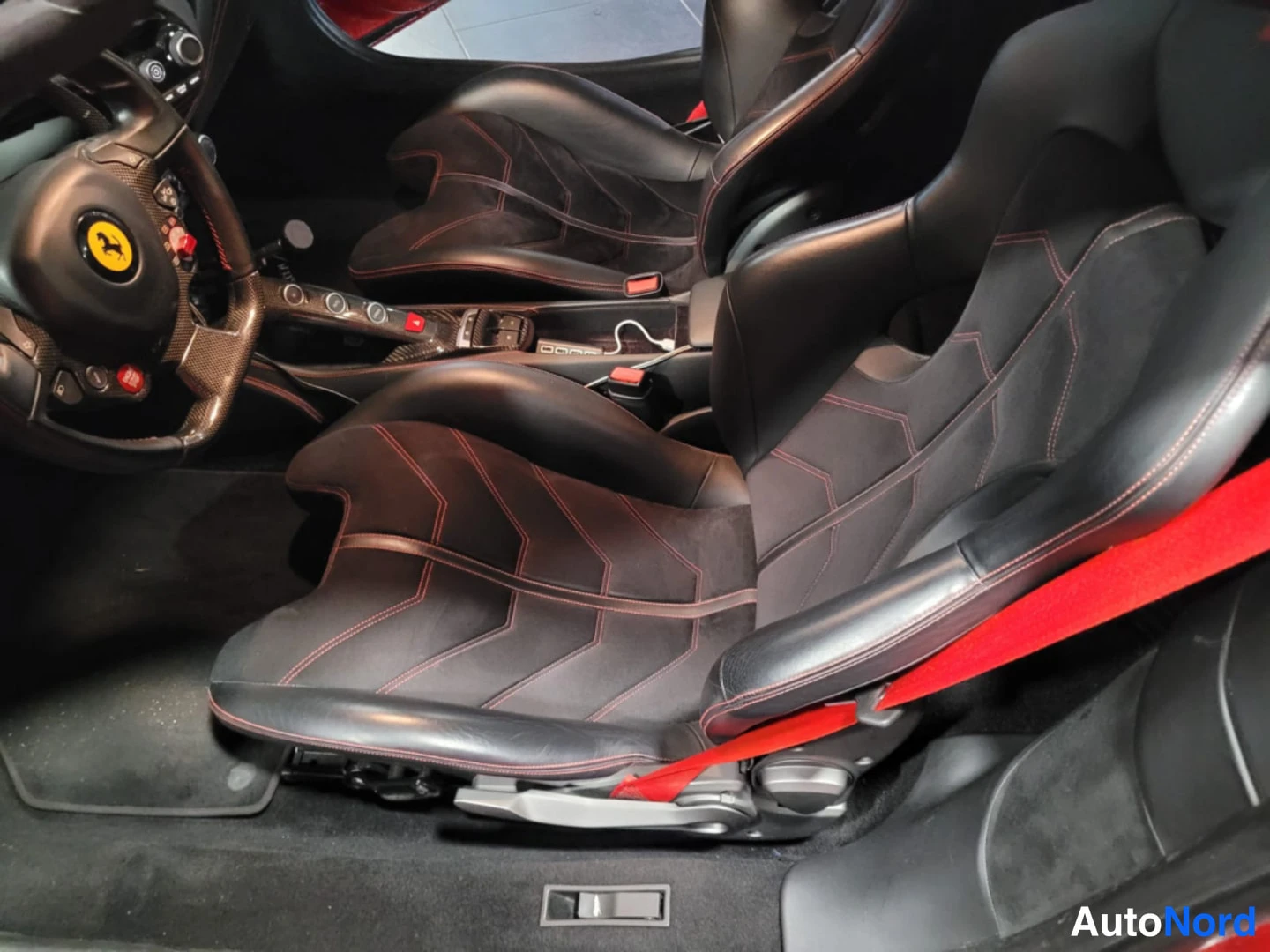 Yksityiskohta: Ferrari 488:n sisätilat: urheiluistuimet mustalla nahalla ja punaisilla tikkailla, punaiset hihnat ja ohjauspyrstä Ferrari-tunnuksella.