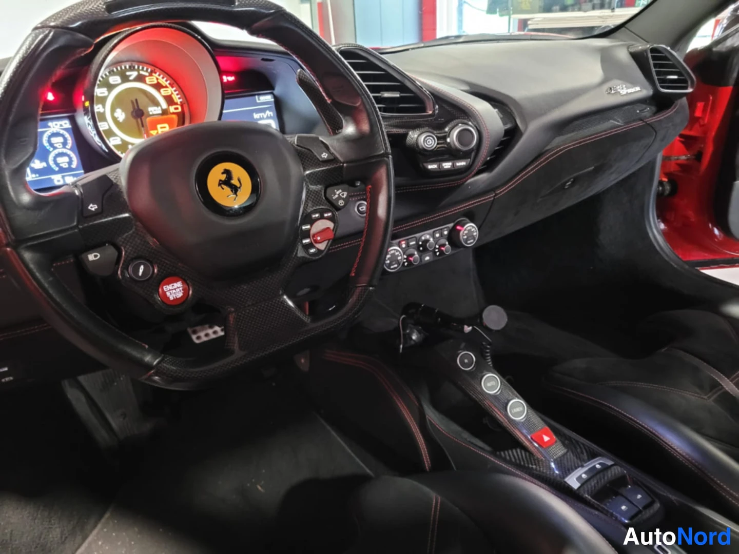 Muu: Ohjaamo vasemmalta kuvattuna: Ferrari-ohjauspyörä, analoginen kierroslukemittari, näyttö 'km/h', punainen ENGINE START STOP -painike, hiilikuituvaihtotunneli ja