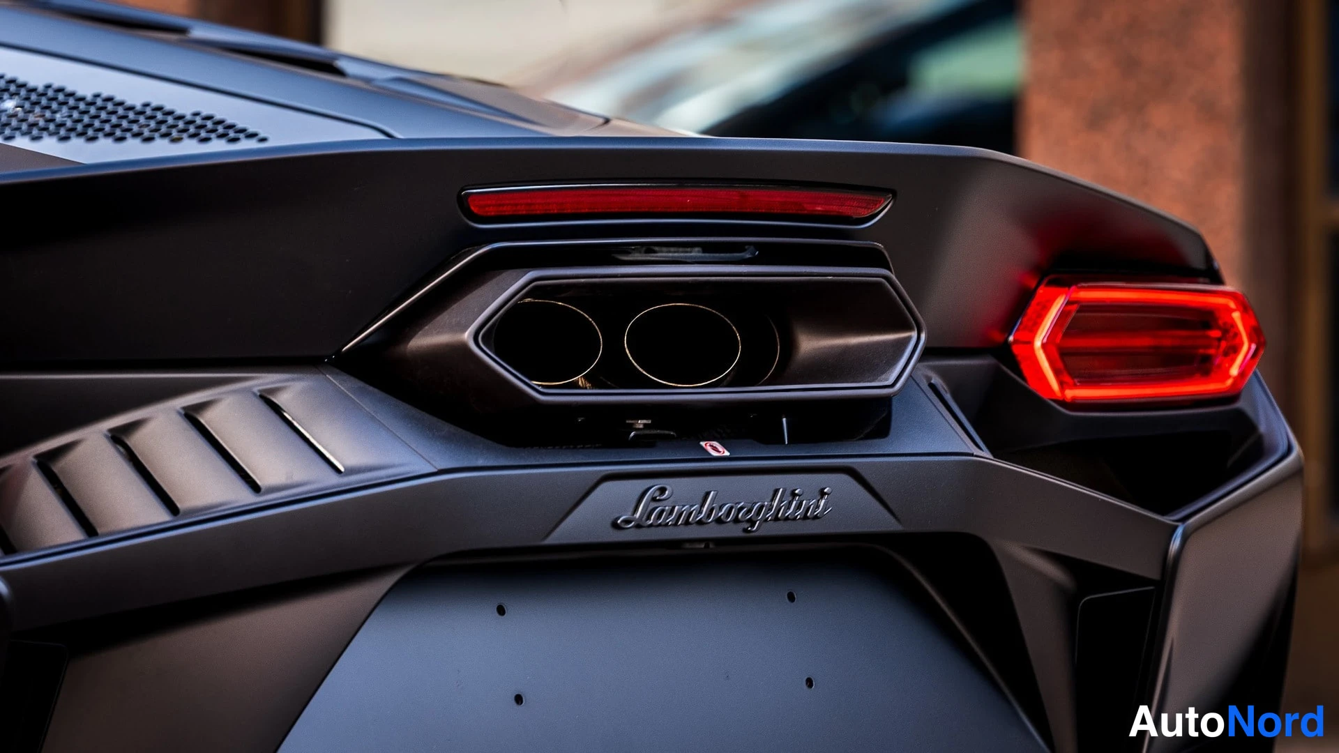 Takaa: Auton takapään lähikuva: keskitetty pakoputkisto, Lamborghini-merkki ja punainen takavalo