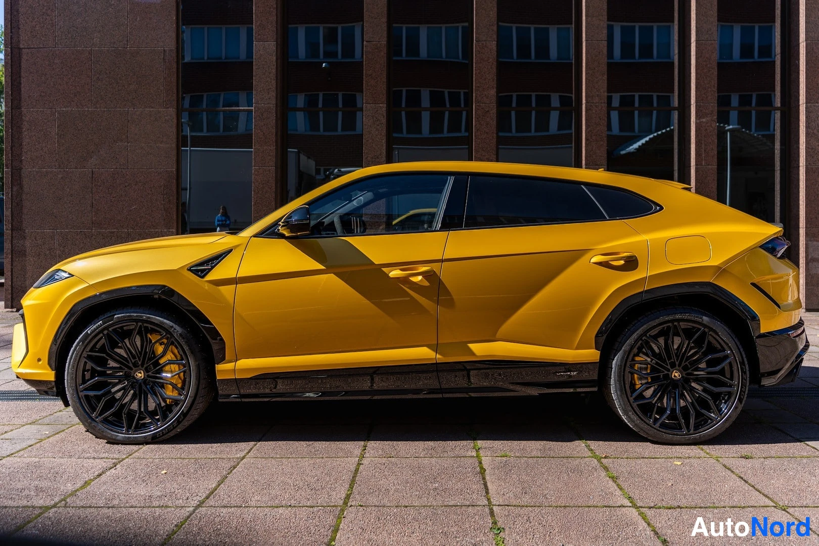 Sivulta: Keltainen Lamborghini Urus sivusta, mustat korilevyt ja mustat vanteet.