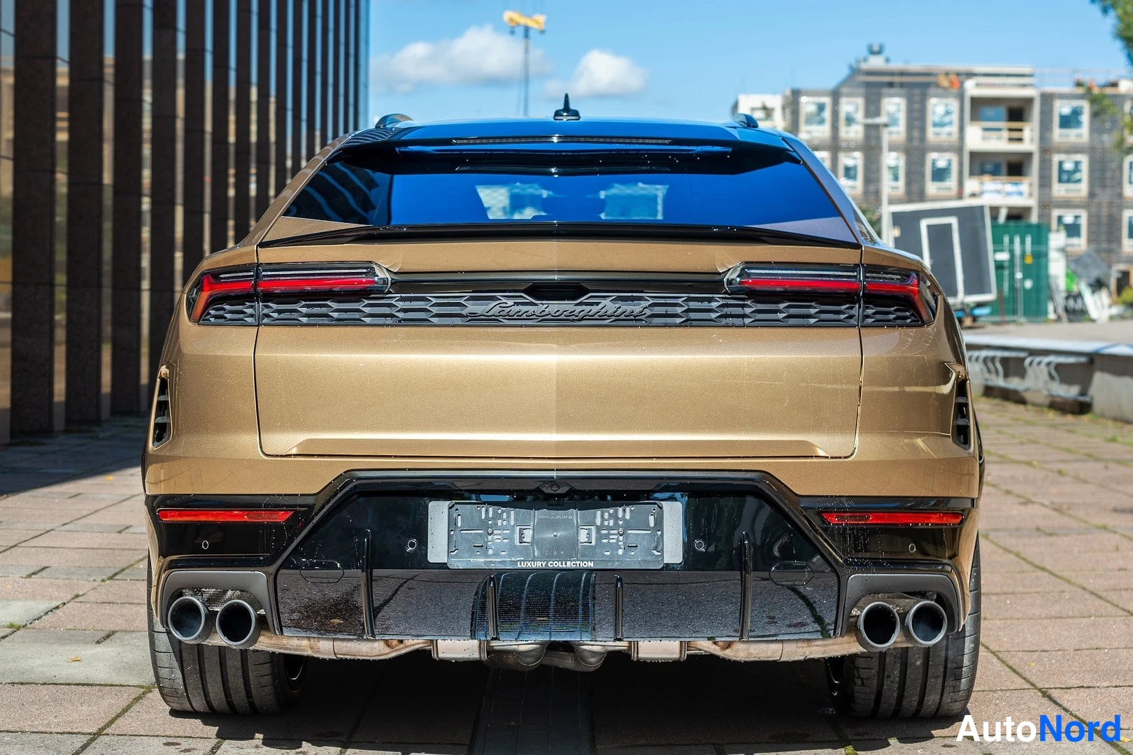 Takaa: Kullanvärinen Lamborghini Urus takaa taakse kuvattuna; näkyvissä takavalot, Lamborghini-teksti, diffuusori ja neljä pakoputkea.
