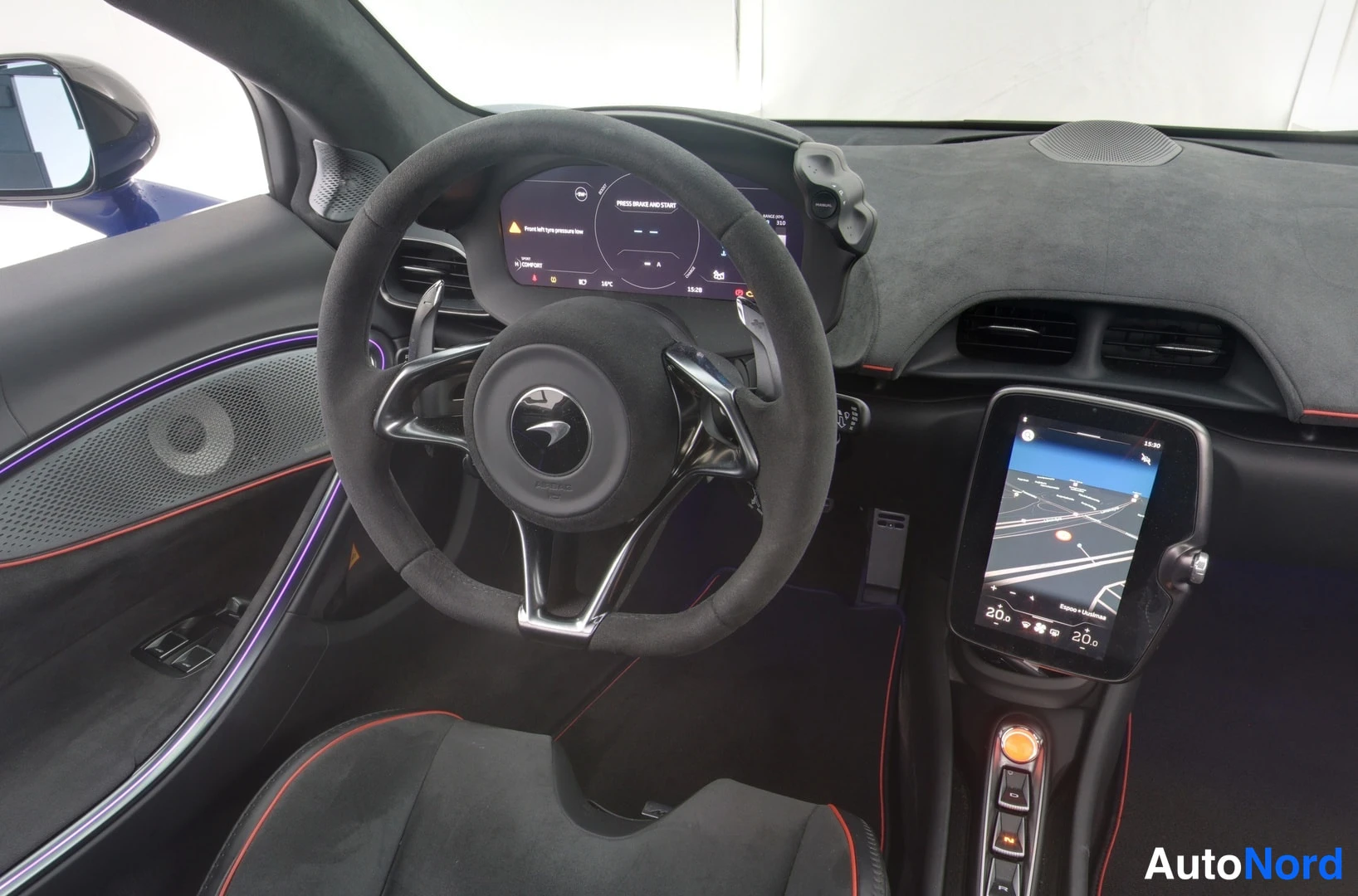 Muu: Ohjaamossa näkyvät McLaren-ohjauspyörä, nestekidenäyttö ja keskikonsolin kosketusnäyttö, jolla näkyy navigointikartta.