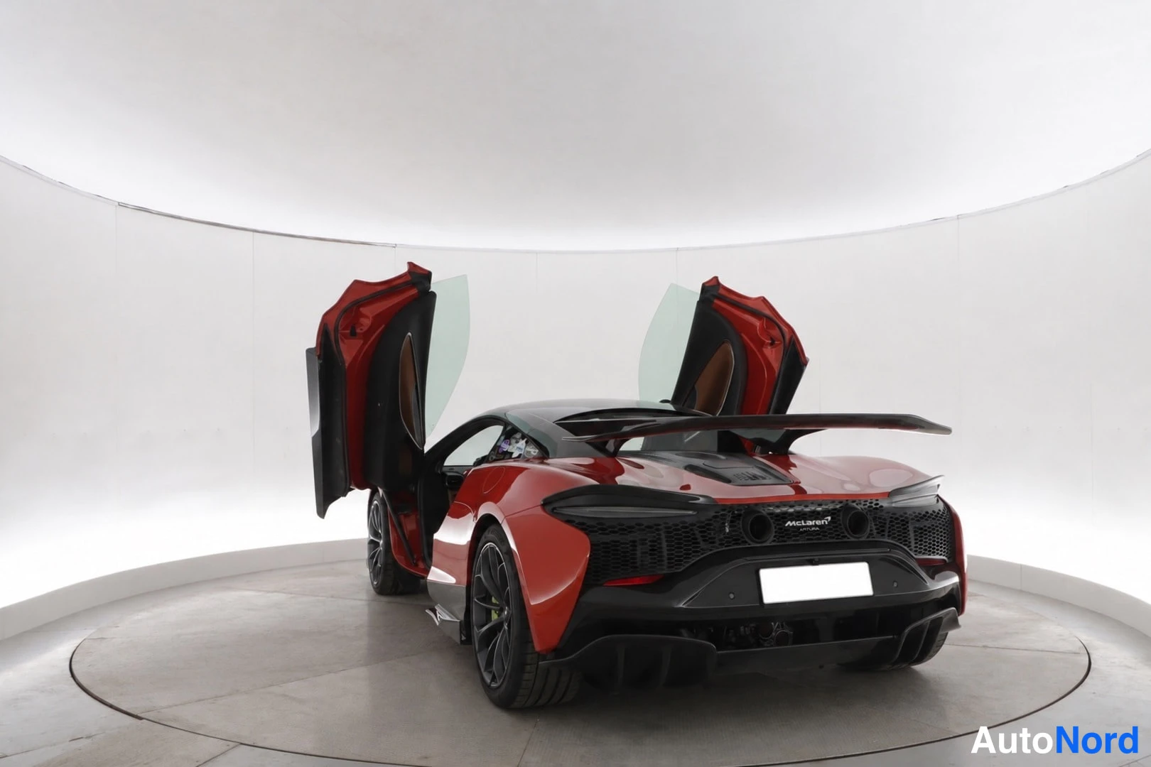 Takaa: Punainen urheiluauto takaa, McLaren-teksti perällä ja takasiipi; molemmat ovet auki.