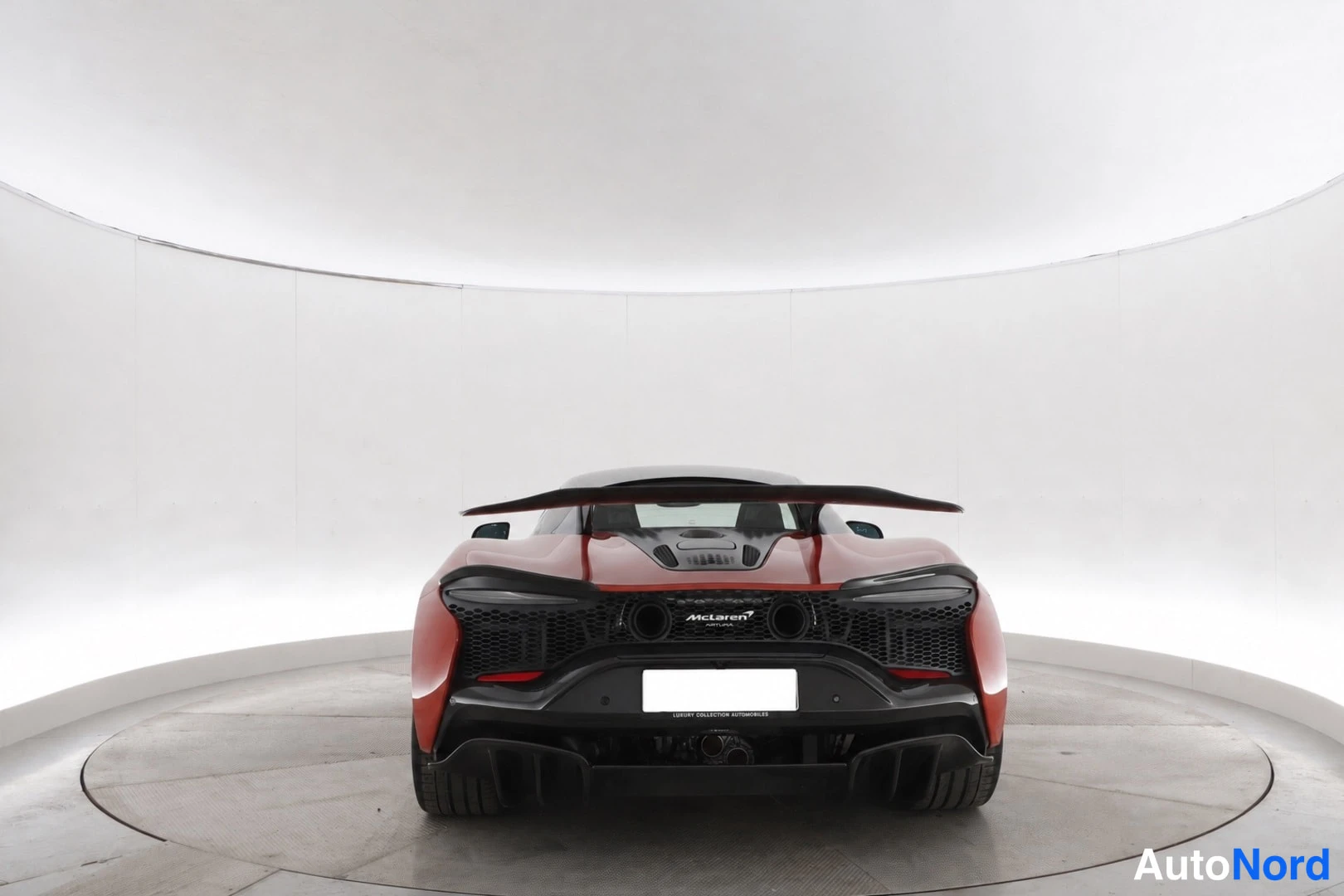 Takaa: Punainen urheiluauto suoraan takaa kuvattuna; McLaren-teksti tailless-tekstinä takaritilässä ja musta takasiipi.