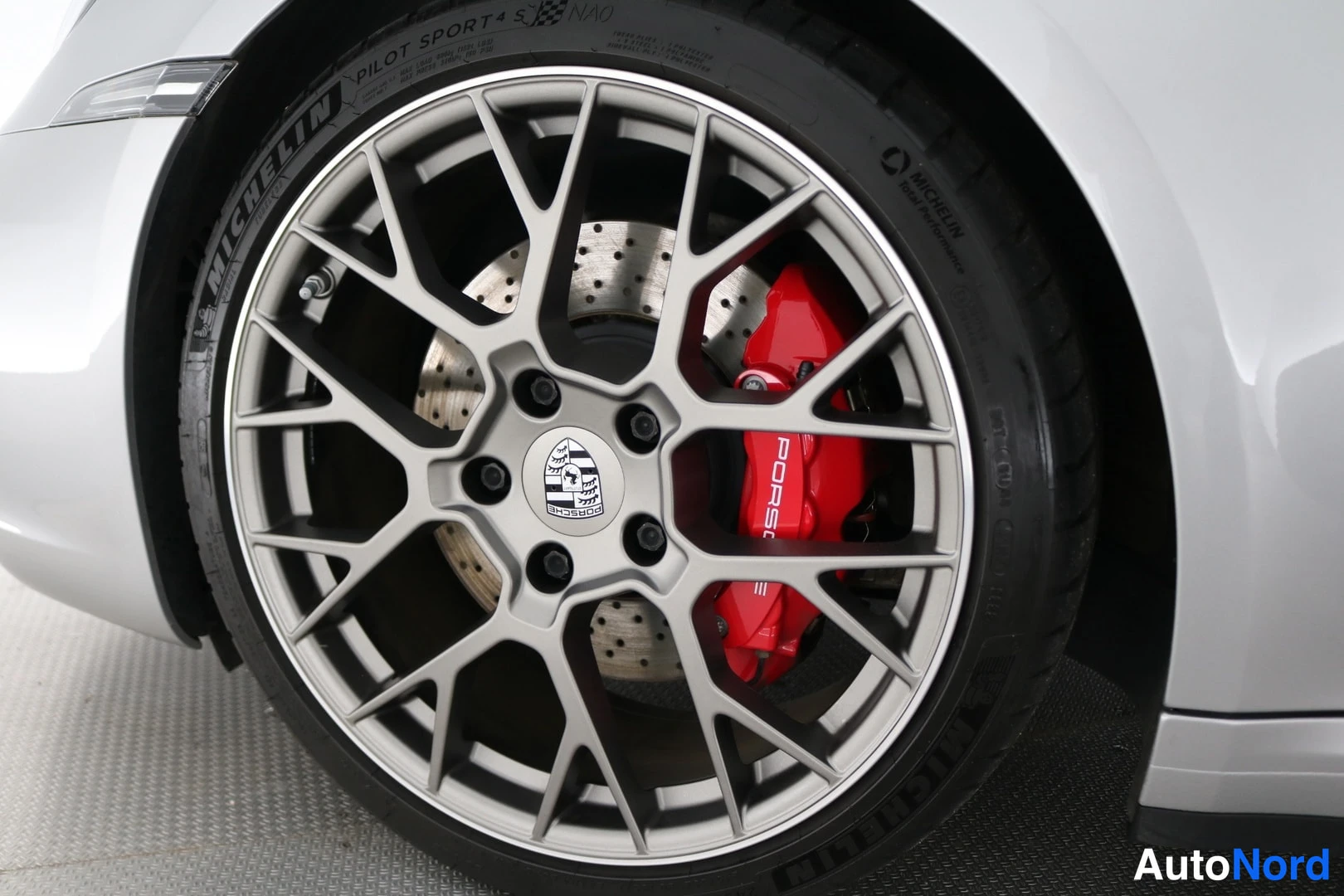 Muu: Auton pyörä lähikuvassa: harmaa Porsche-vanne, punainen jarrusatula ja Michelin Pilot Sport 4 S -rengas
