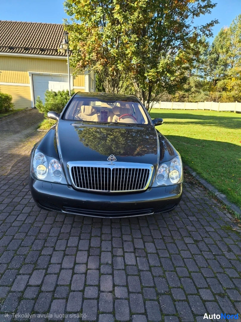 Edestä: Tummanharmaa sedanin etunäkymä, kromimaski ja etupuskurit näkyvät, sisätilat beige.