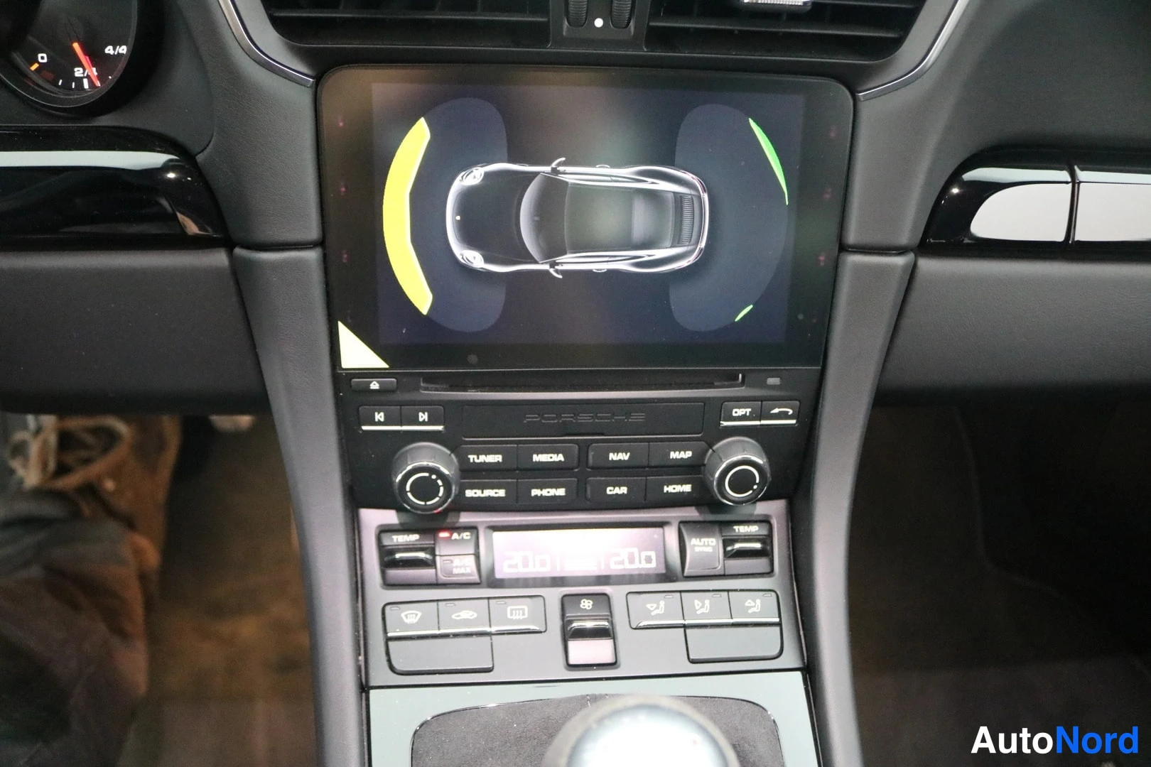 Muu: Porsche-mittaristosäleikön alalaita ja keski-console-napit: TUNER, MEDIA, NAV, MAP, SOURCE, PHONES, CAR, HOME, OPT, ympäristönäyttö.