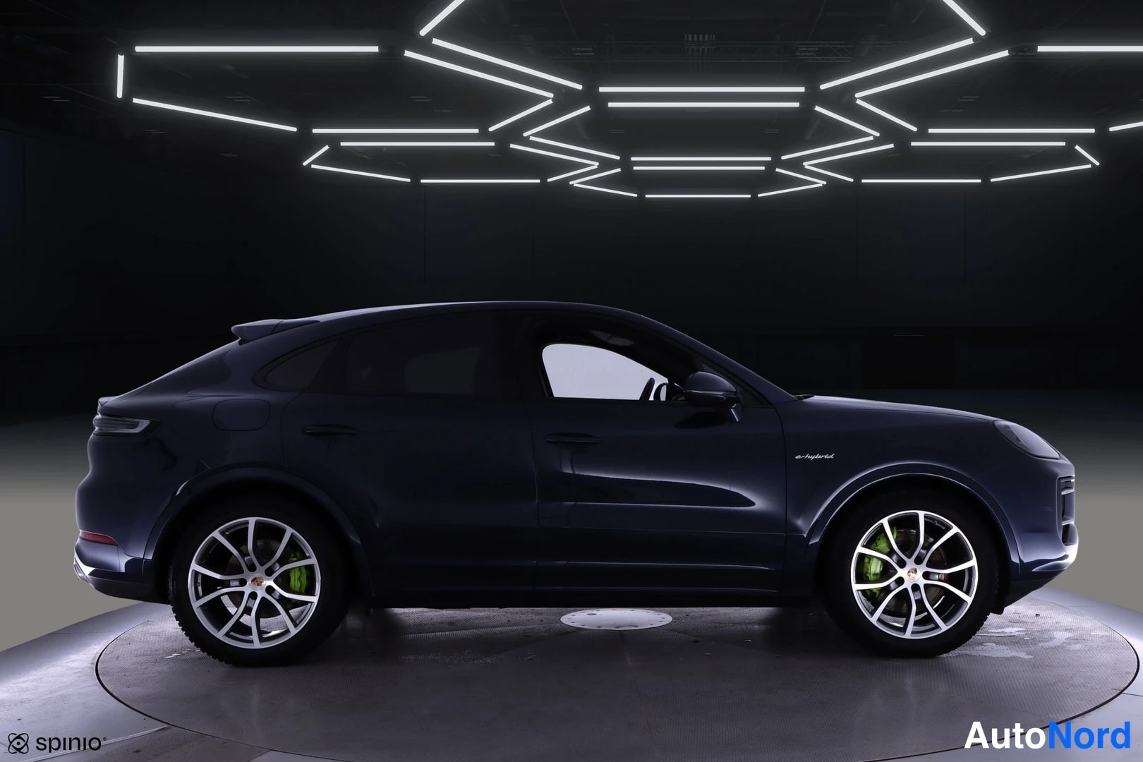 Sivulta: Porsche Cayenne Coupén sivuprofiili tummansinisellä maalilla studiokuvassa, keulasuunta oikealle.