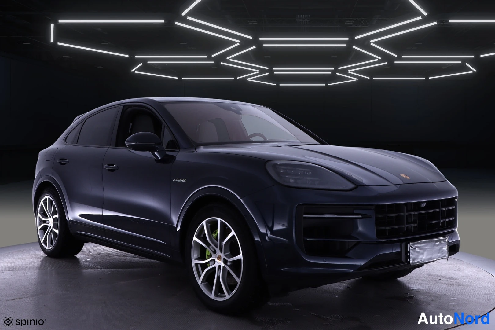 Etuviisto, nokka oikealle: Porsche Cayenne Coupén kolmannesetukäymä edestä oikealta, tummansininen runko ja hopeiset vanteet studiokuvassa.