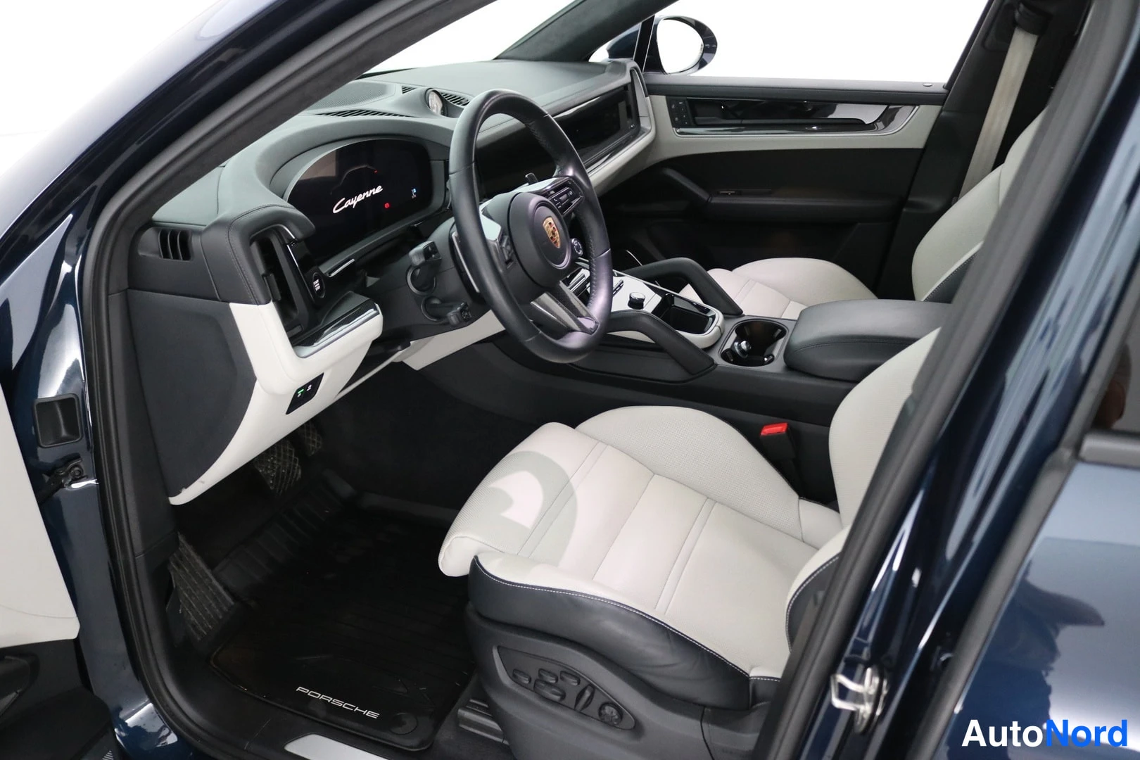 Muu: Porsche Cayennen ohjaamo sivulta: valkoiset penkit, Porsche-merkkinen mattotassu ja mittaristön näyttö.