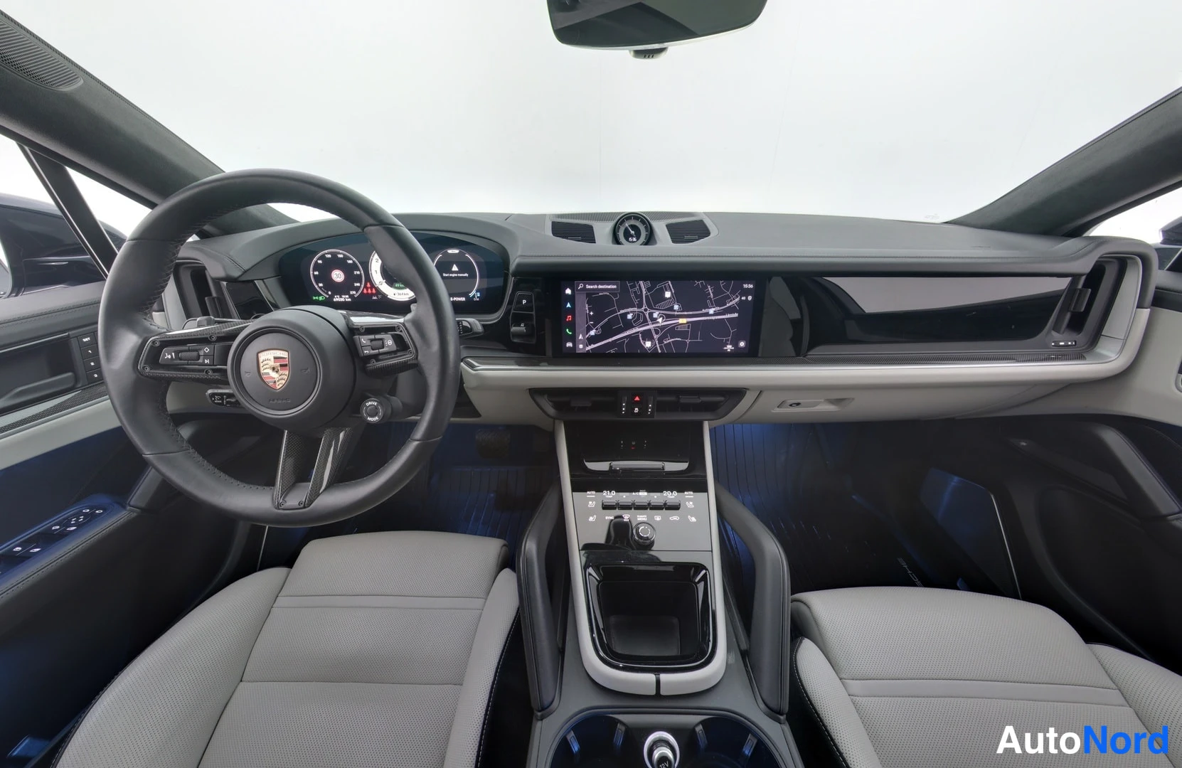 Muu: Porsche Cayennen ohjaamo edestä: Porsche-ohjauspyörä, polttoaine/hybridi-mittarit, kartta näyttävä keskinäyttö ja keskihallinta.