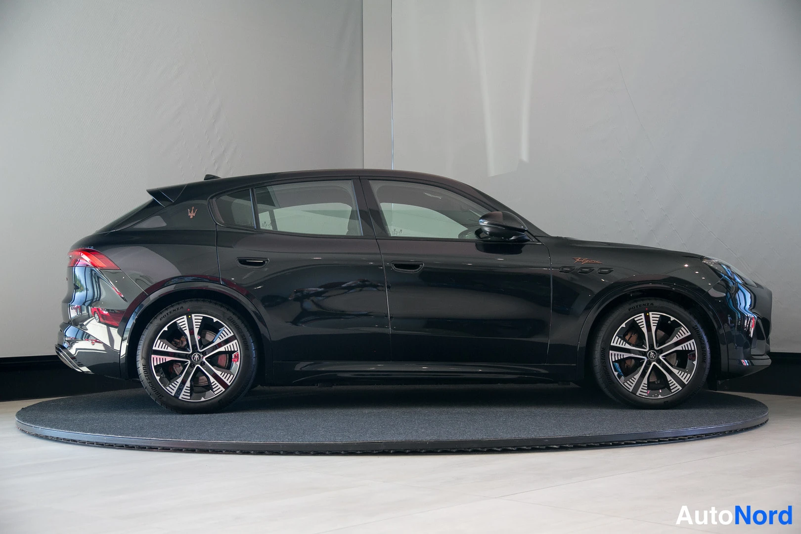 Sivulta: Mustan Maserati Grecale -maasturin sivuprofiili valokuvastudiossa pyörivällä alustalla.