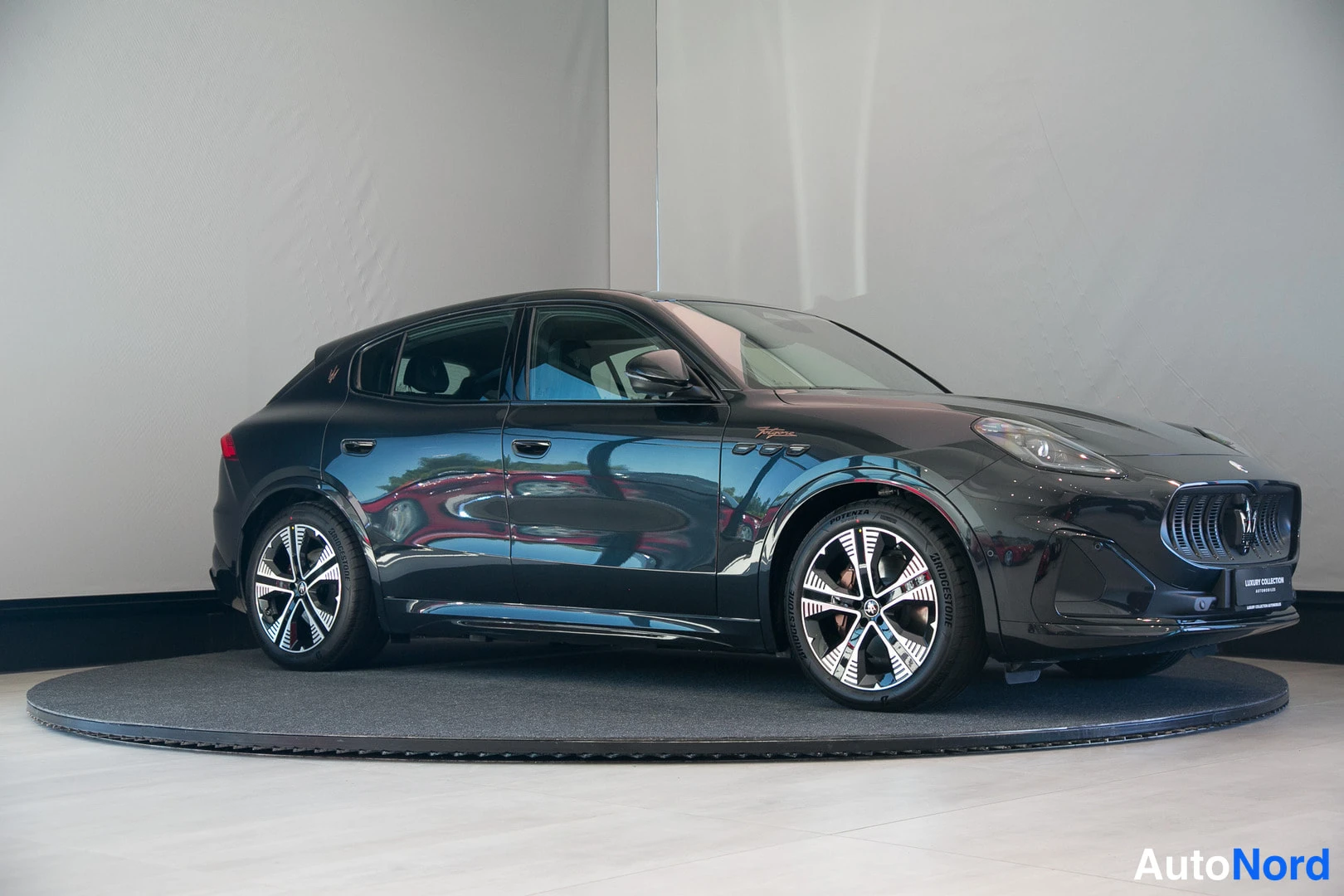 Etuviisto, nokka oikealle: Mustan Maserati Grecale -maasturin etukulma, keula osoittaa oikealle, studiossa pyörivällä alustalla.