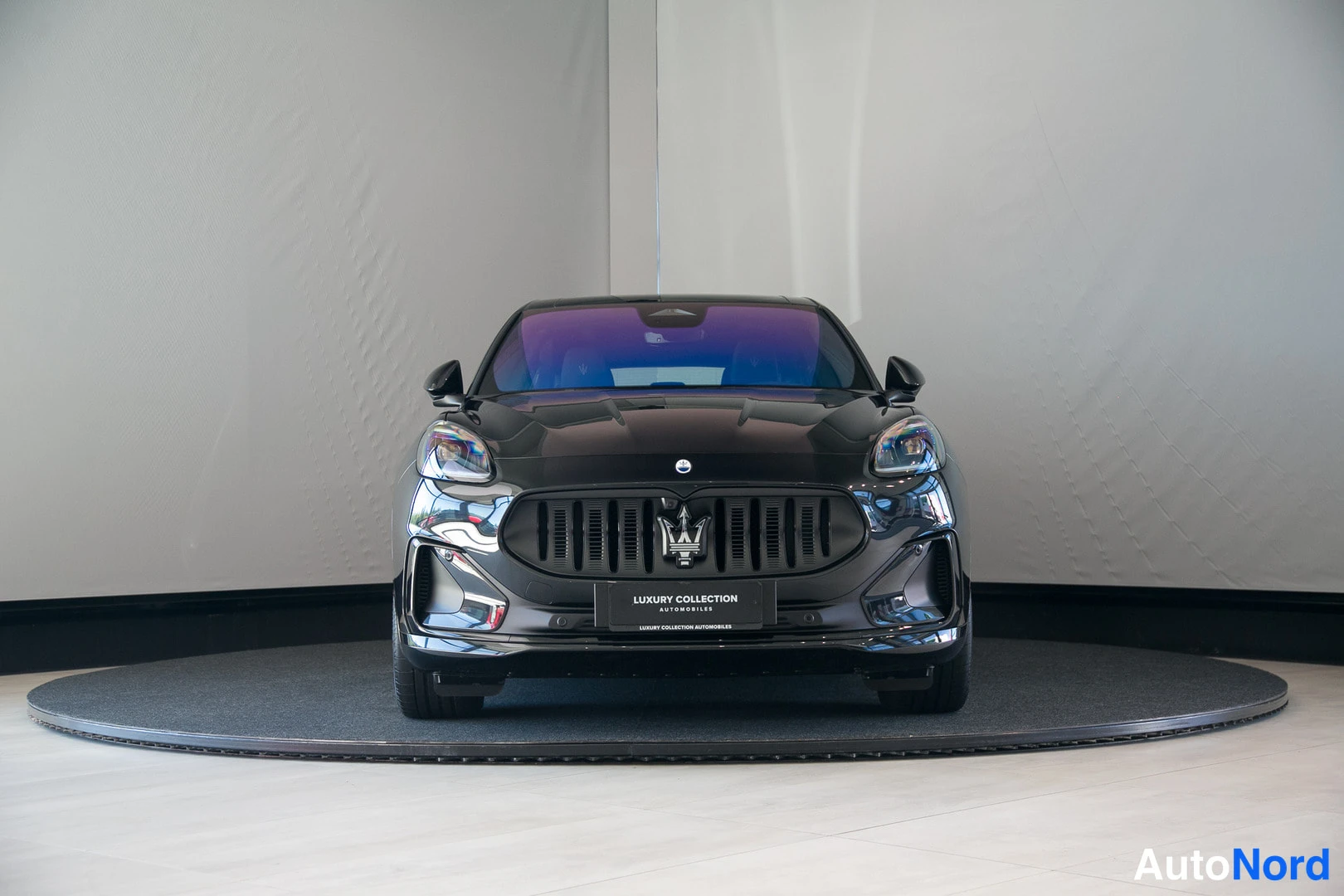 Edestä: Mustan Maserati Grecale -maasturin suora etänäkymä, jossa näkyy etusäleikkö ja Maseratin merkki, studiossa.