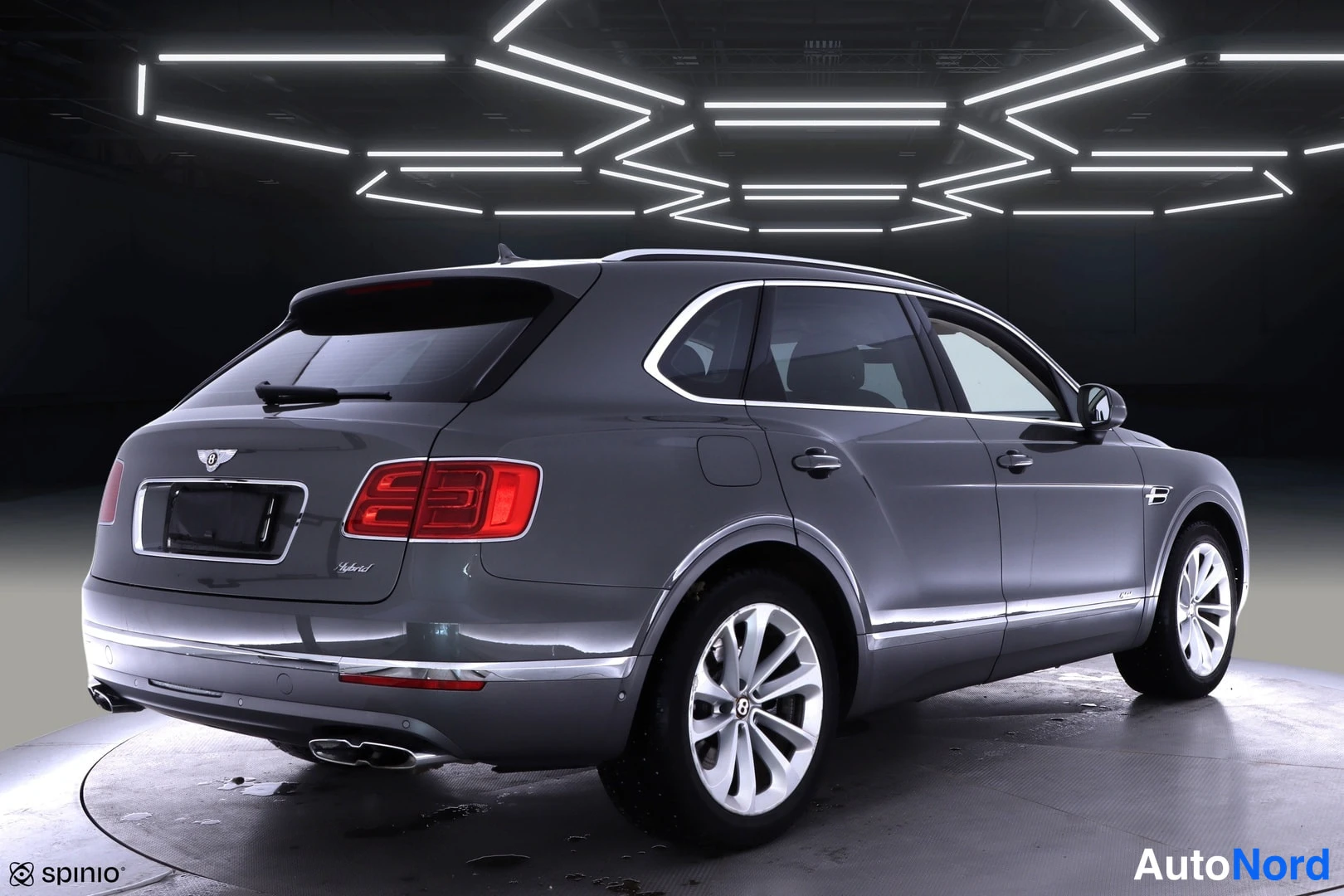 Takaviisto: Bentley Bentayga takakulma vasemmalta, punaiset takavalot ja kromilista studiossa.