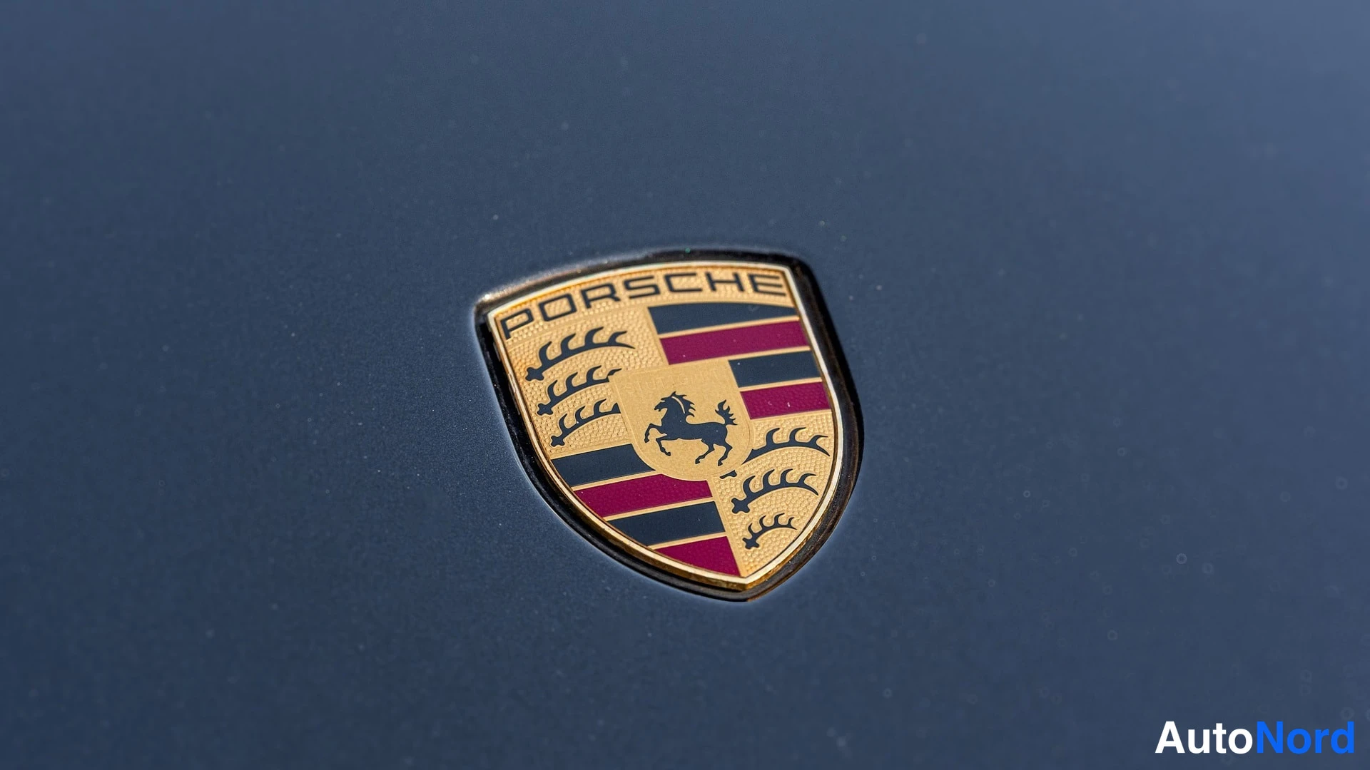 Edestä: Porsche-merkki lähikuvassa tummansinisellä konepellillä