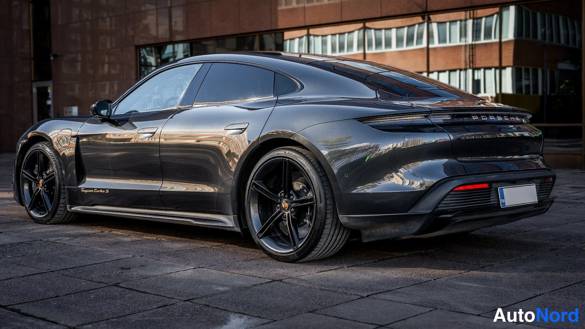 Takaviisto: Taka-aikalataus takaa yläviistosta: tummanharmaan Porsche-sedanin perä ja vasen kylki