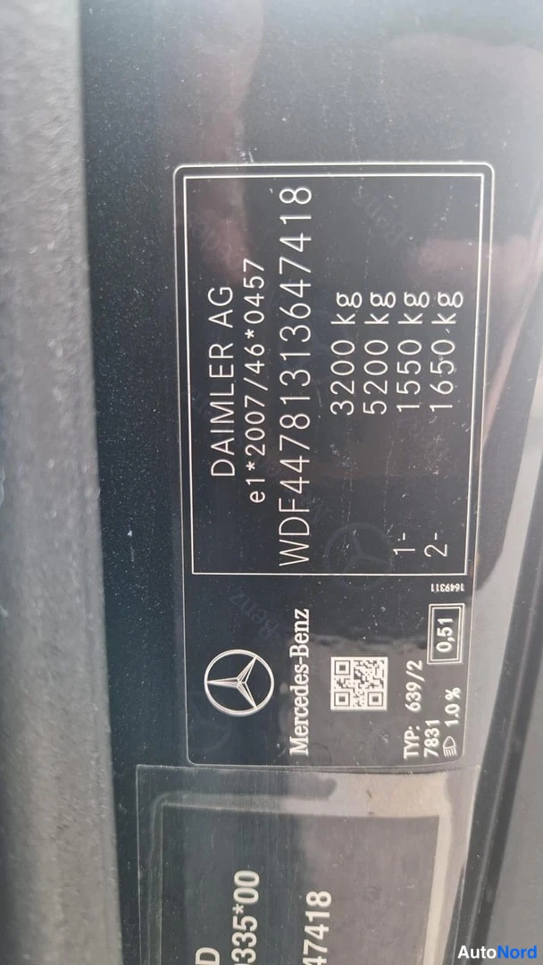 Muu: Ajoneuvon.Runartunnus-tarrakuvaa lähikuva, jossa näkyy VIN ja Mercedes-Benz-logo.