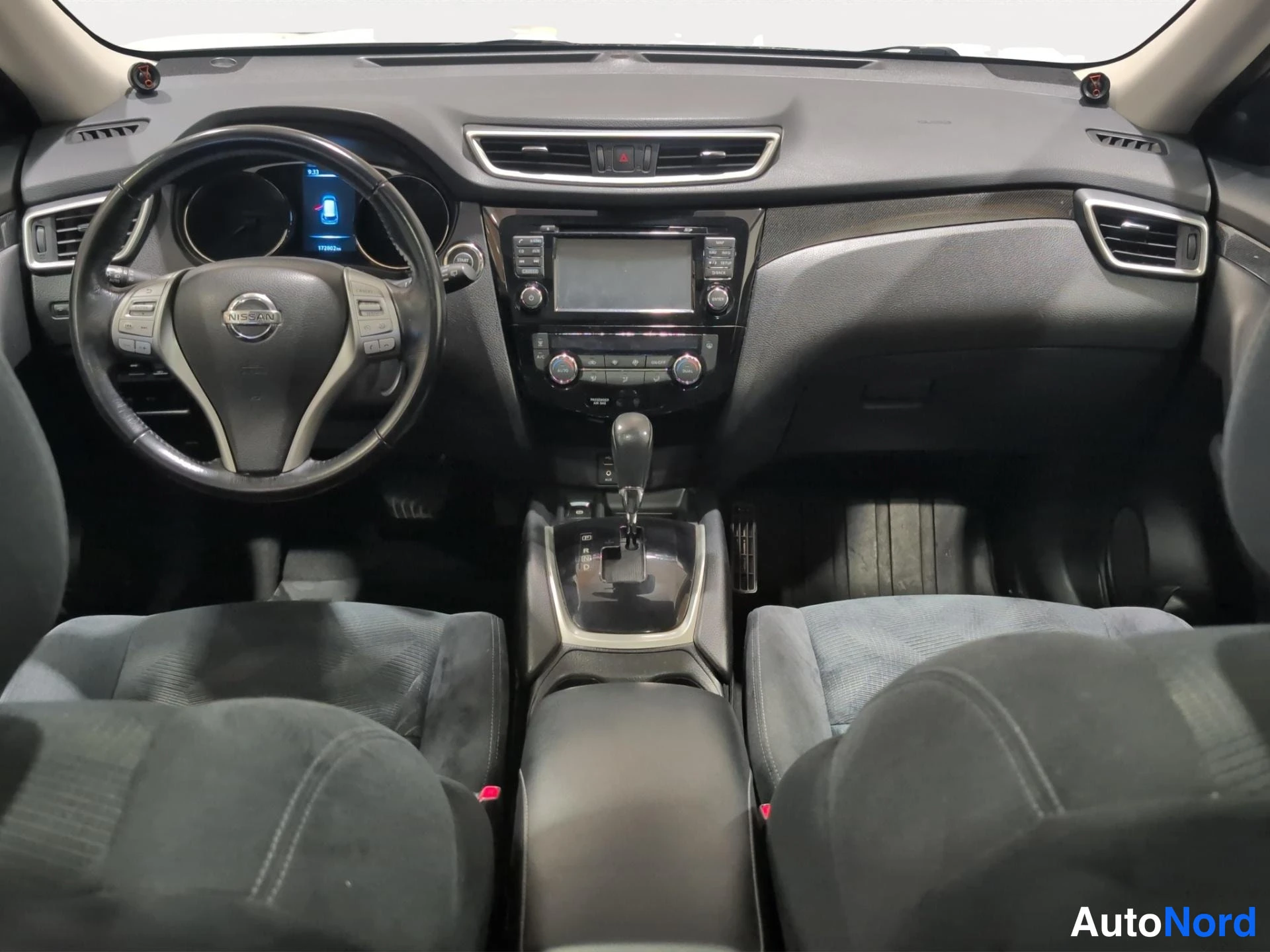 Edestä: Nissan X-Trails ohjaamo edestäpäin: monitoiminappuloilla varustettu ohjauspyörä, keskikonsolin automaattivaihtoeja ja kosketusnäyttö.