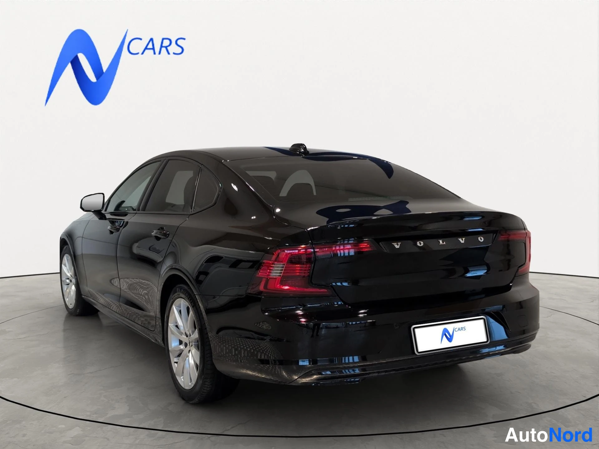 Takaviisto: Musta Volvo S90 -sedan takaviistosta vasemmalta kuvattuna; takamoottiin kilpi, VOLVO-teksti ja hopeiset vanteet.