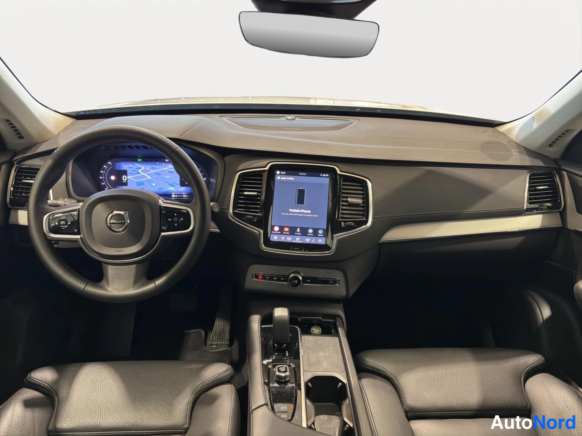 Muu: Ohjaamo etualasta kuvattuna: Volvo-ohjauspyörä, digitaalinen mittaristo ja keskinäyttö, jossa Apple CarPlay -ruutu. Keskellä on vaihteenvalitsin ja konsoli, ede