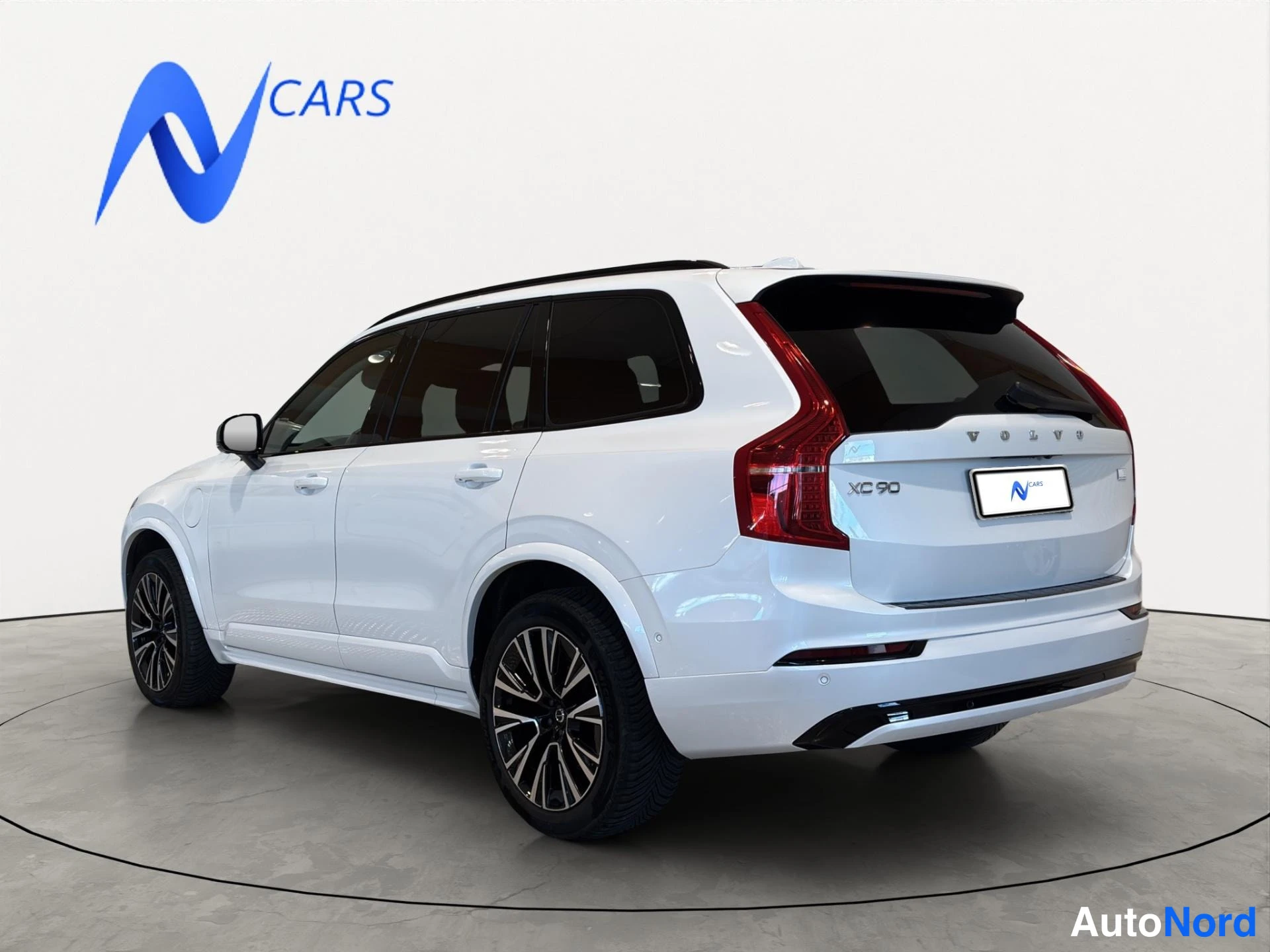 Takaviisto: Valkoisen Volvo XC90:n takapää ja oikea sivu kuvattuna studiotaustaa vasten.