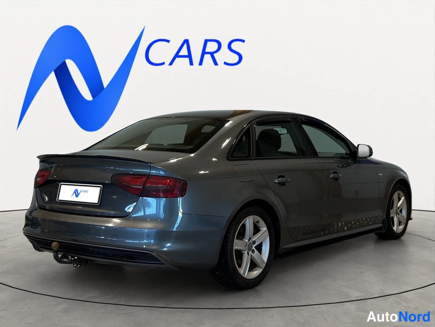 Takaviisto: Audi A4 -sedan takakulmasta, perä vasemmalla, tummanharmaa koripaneelit, valkoinen tausta.