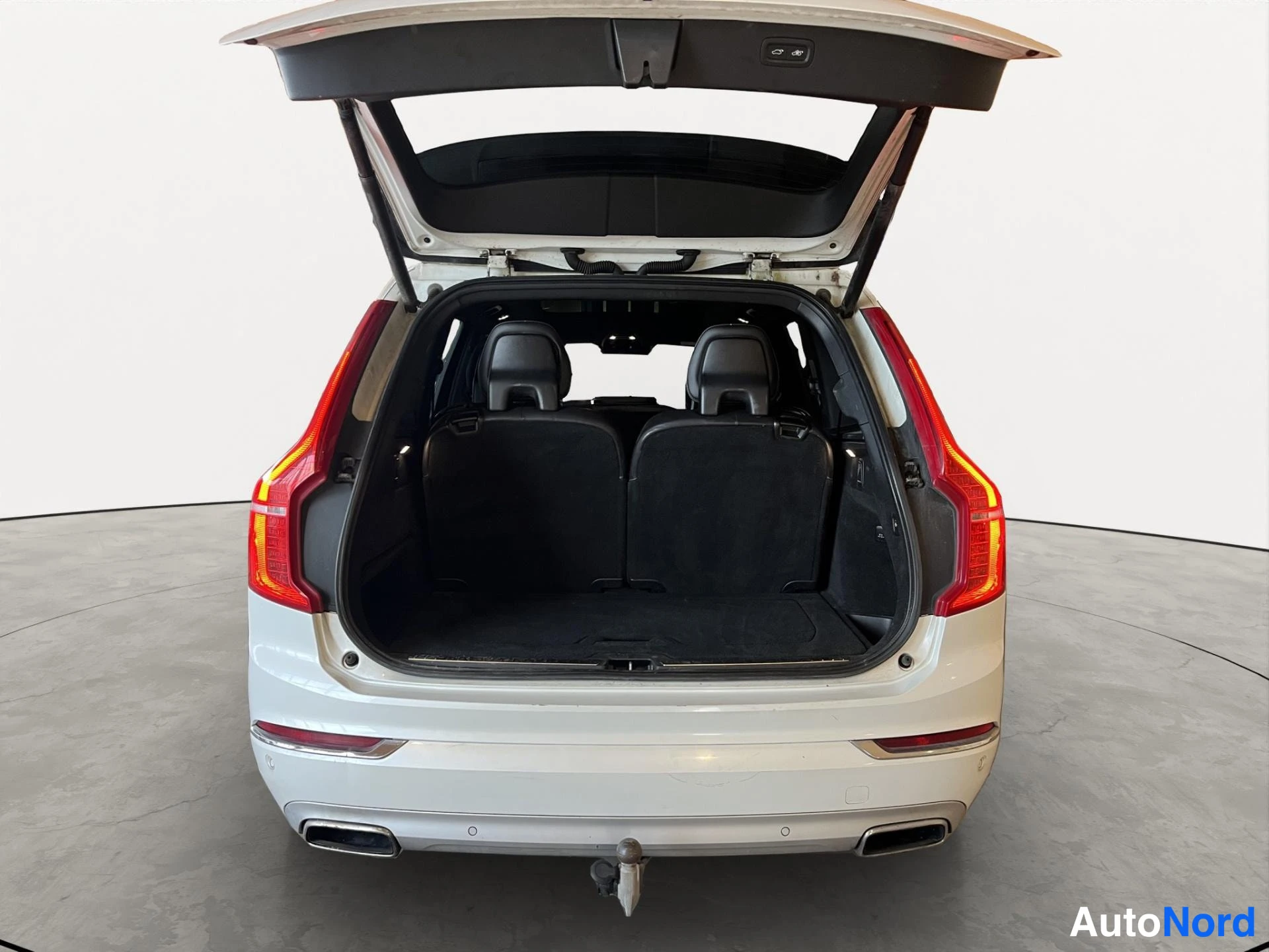 Takaa: Valkoisen Volvo XC90:n tavaratila avoimella takaluukulla; tummat takaselkänojat ja mattapinta tavaratilassa.