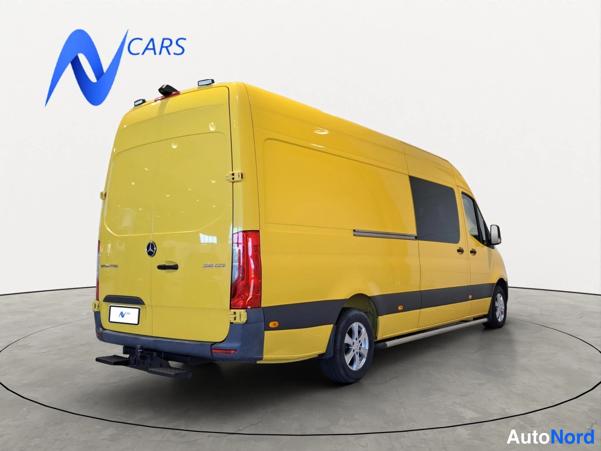 Takaviisto: Mercedes-Benz Sprinter -pakettiauto takaa ja sivulta kolmannelta takakulmalta kuvattuna, takaluukut ja keltainen korit peitetty pyörän kuormausaukko näkyy sivul