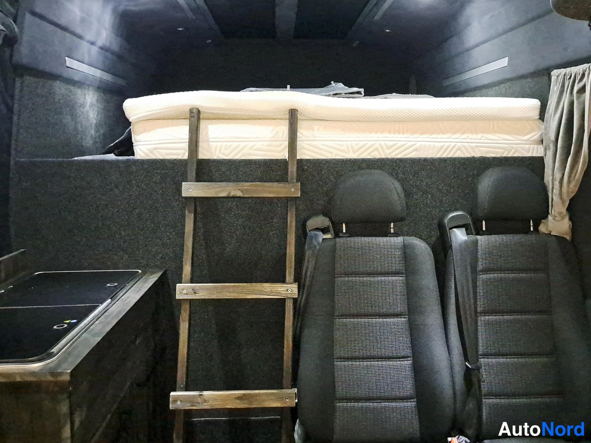 Muu: Auton sisätilat: ylätilassa sänky luukun kannen päällä, edessä kaksi tummalla kangasverholla varustettua etuistuinta, asennettu puinen tikkaat.
