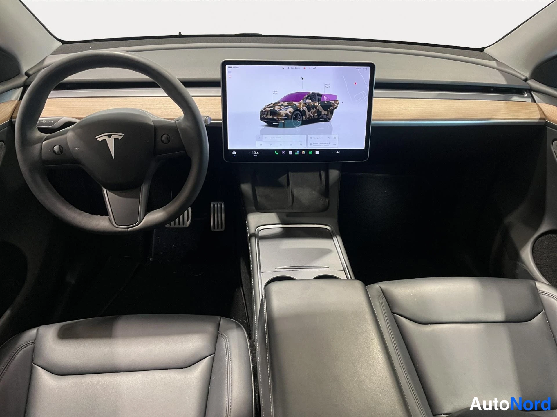 Yksityiskohta: musta nahkaverhoilu, Tesla-ohjauspyörä ja keskellä iso kosketusnäyttö, jossa auton kuva.